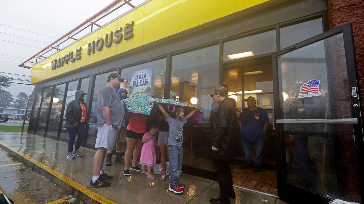 Luke Churchill stands with his wife, Mary, and their children, Katie, Liam and Raighan, as they wait in the rain outside an open Waffle House in Wilmington, N.C., after Hurricane Florence on Sept. 16, 2018. The Waffle House Index is a gauge of how severe a storm can be.