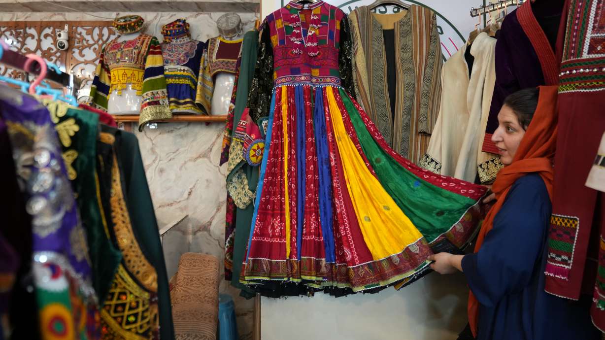 Tahmina Mangal displays a traditional Afghan dress at her clothing shop in Kabul, Afghanistan, Sunday. Twenty-five years after the invasion and five years after the chaotic U.S. withdrawal from the country, the Taliban are firmly back in control of Afghanistan.