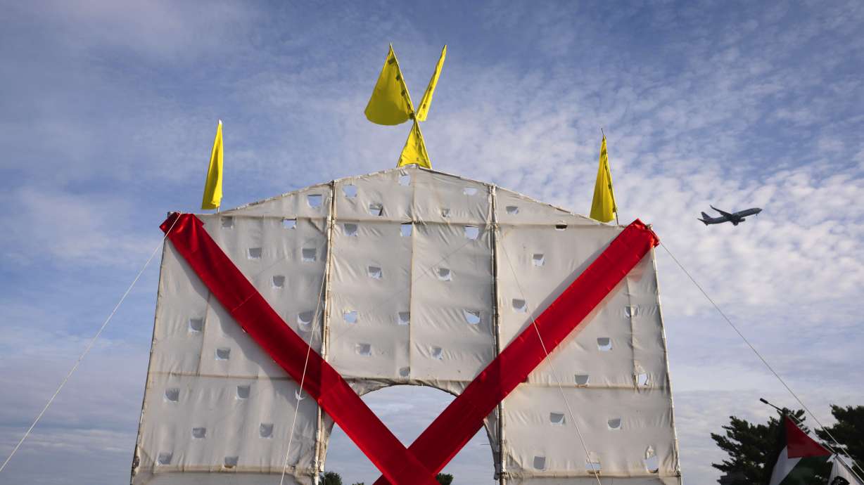 A plane flies over an anti-arch structure lifted up by demonstrators at Memorial Circle to protest the proposed Triumphal Arch, Thursday, Oct. 1, in Arlington, Va. The Arlington County Board filed a lawsuit opposing the construction of the Triumphal Arch, becoming the first governmental body to take legal action against the planned monument.