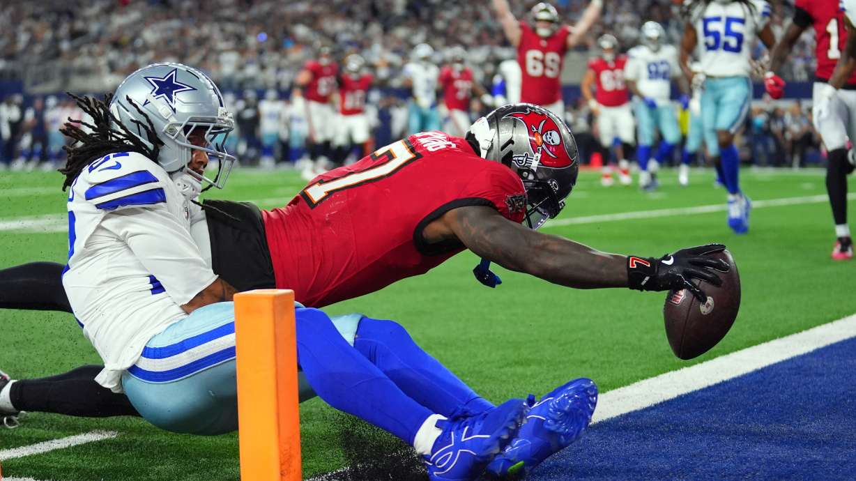 Tampa Bay Buccaneers running back Bucky Irving (7) dives past Dallas Cowboys defensive back Reddy Steward (27) for a touchdown in the first half of an NFL football game in Arlington, Texas on Thursday, Oct. 8, 2026.
