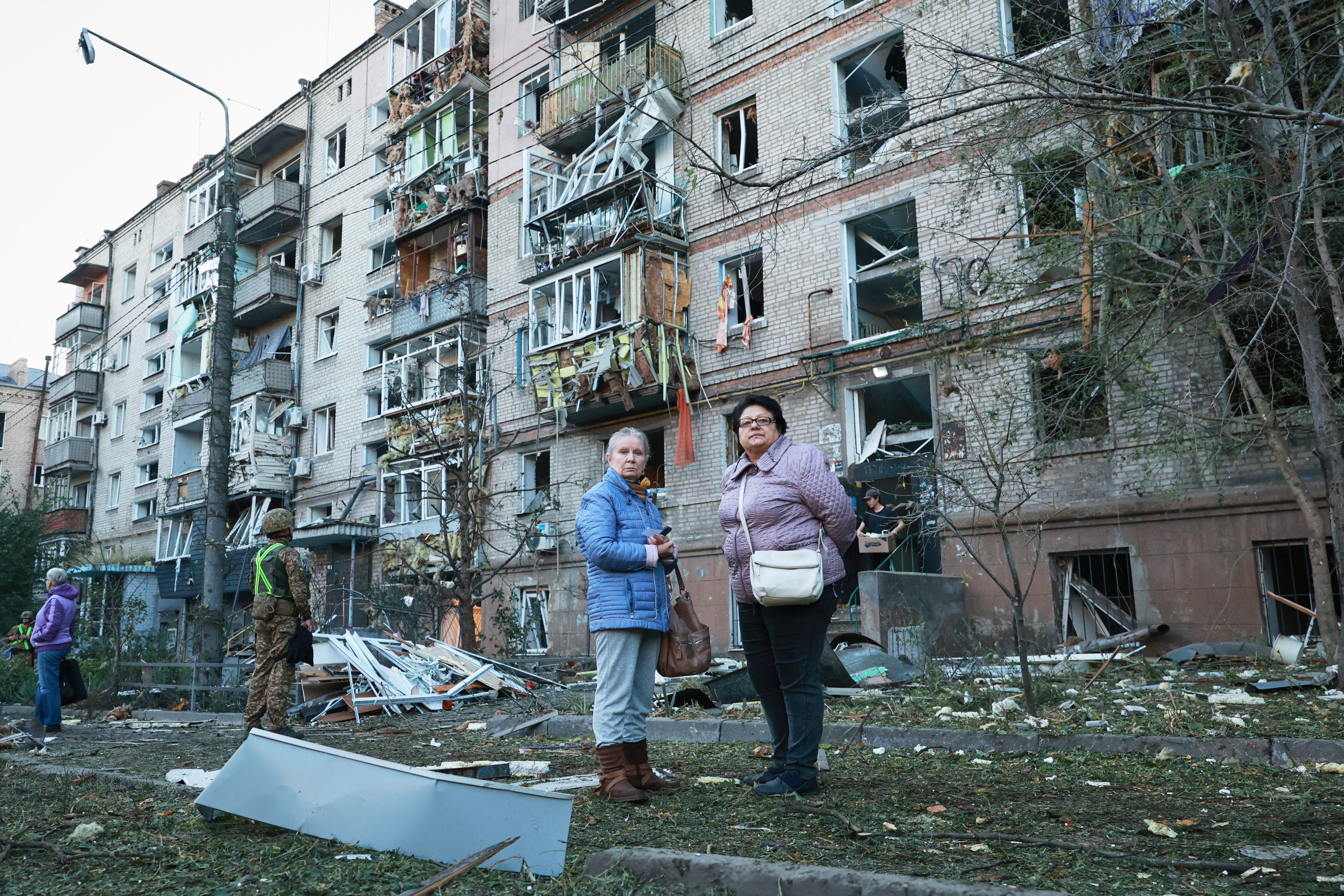 Local residents stand in front of building damaged by a Russian strike on residential neighborhood in Zaporizhzhia, Ukraine, Friday. Three people were killed in the strikes and eight more were wounded.