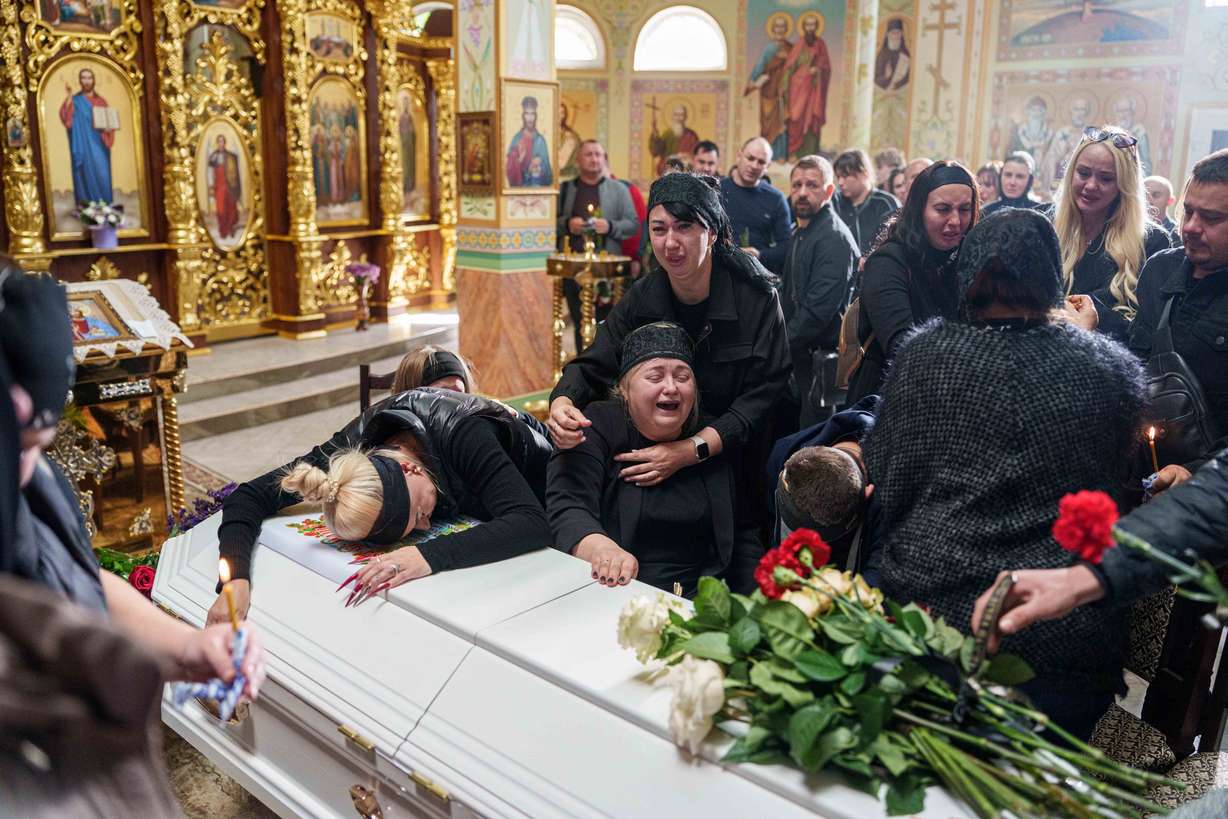 A mother surrounded by family cries sitting by the coffin of her son Illia Honcharenko, 14, killed by a Russian rocket strike on a residential house on Sept. 30, during their funeral, in Vyshhorod, Kyiv region, Ukraine, Oct. 2. More funerals were held on Friday for members of the Ivanchenko family killed in a drone strike.
