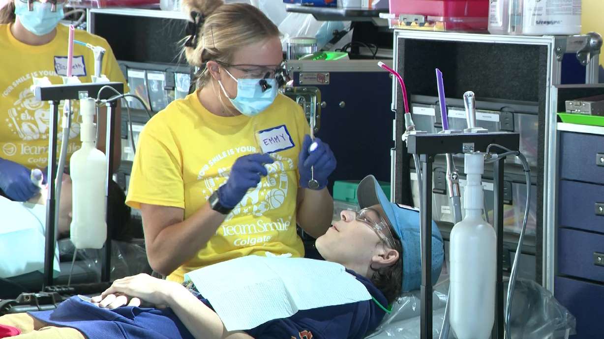 A volunteer with TeamSmile administers dental care to a child at America First Field during the nonprofit's free care event, Friday. The event promoted oral health and connected families with ongoing care.