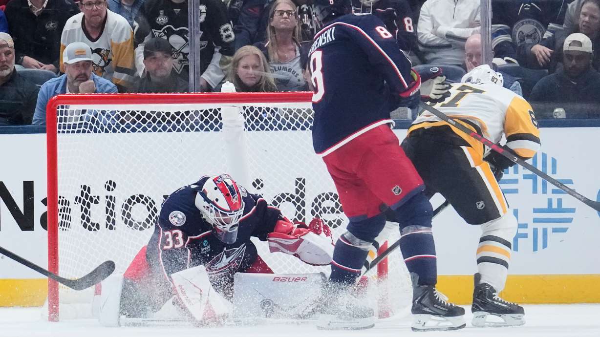 Columbus Blue Jackets goalie Cam Talbot (33) blocks a shot by Pittsburgh Penguins center Sidney Crosby (87), next to Zach Werenski (8), in overtime of an NHL hockey game in Columbus, Ohio, Friday, Oct. 9, 2026.