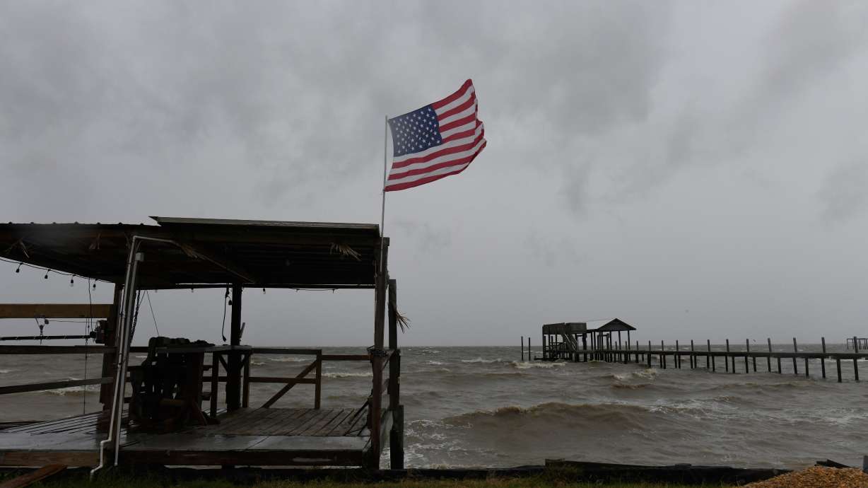 An American flag flaps in the wind generated by the effects of Isaias on an empty beach on Friday in Mon Louis Island, Ala.