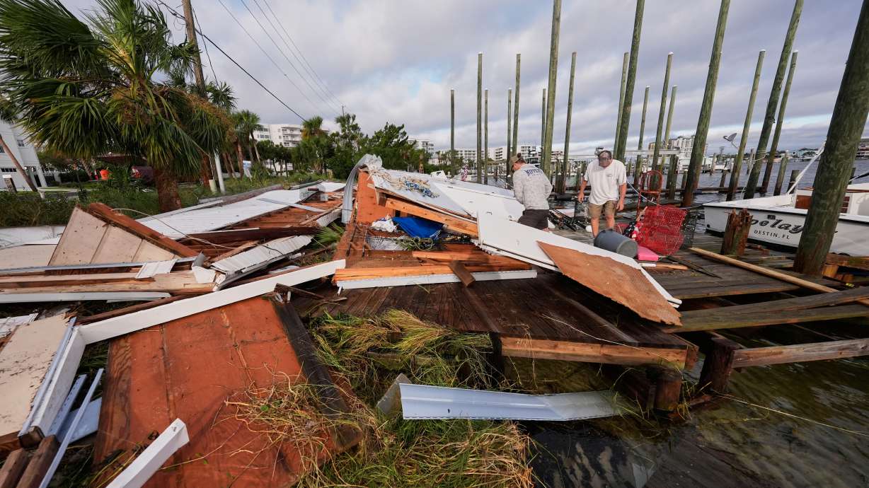 People retrieve belongings from a collapsed boat house in the aftermath of Hurricane Isaias in Destin, Fla., Saturday. At least four people are dead in the wake of the storm.