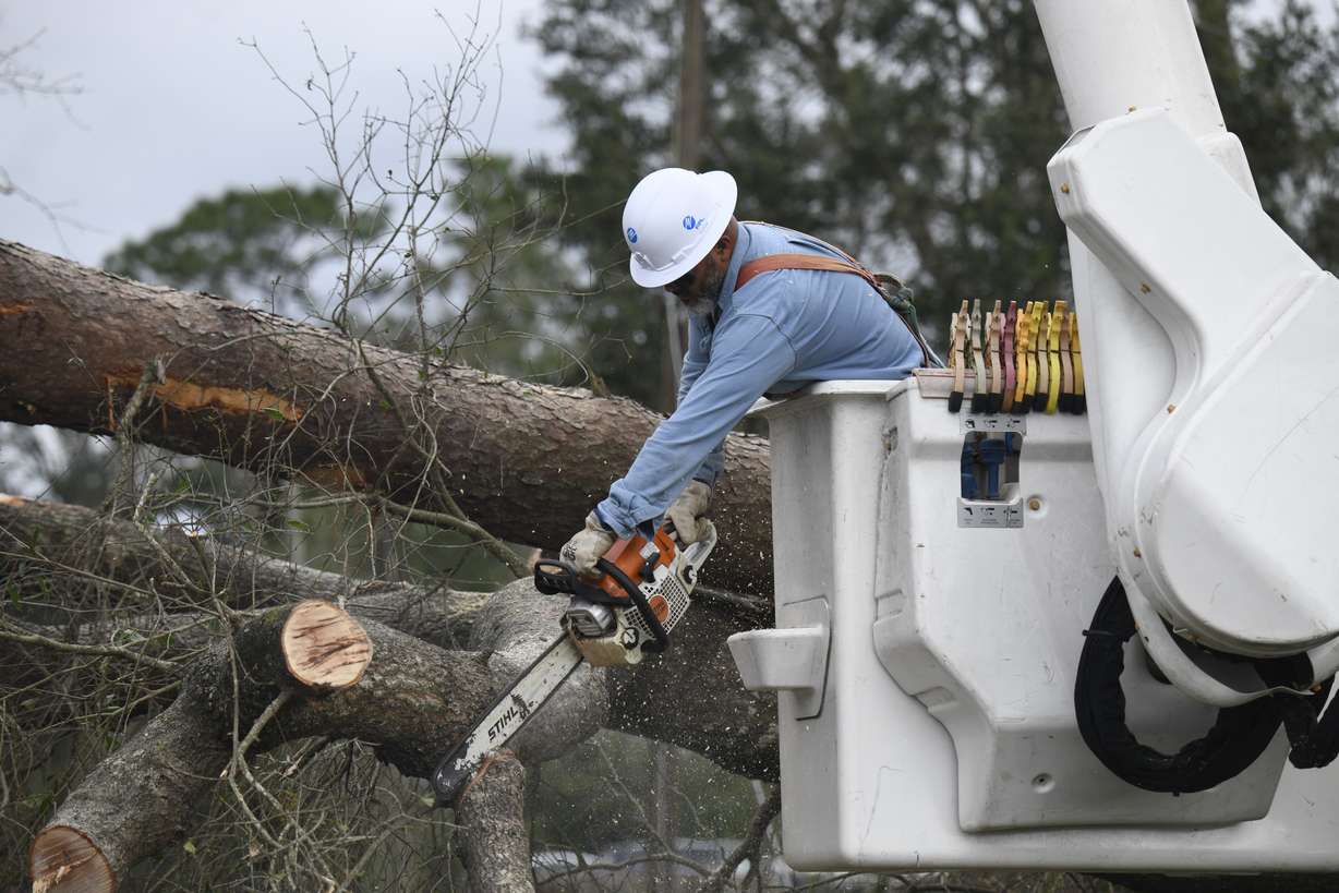 Florida Power & Light worker Yosvany Quintero clears downed tree limbs caused by the effects of Hurricane Isaias on Saturday, in East Milton, Fla. The storm is responsible for four deaths.