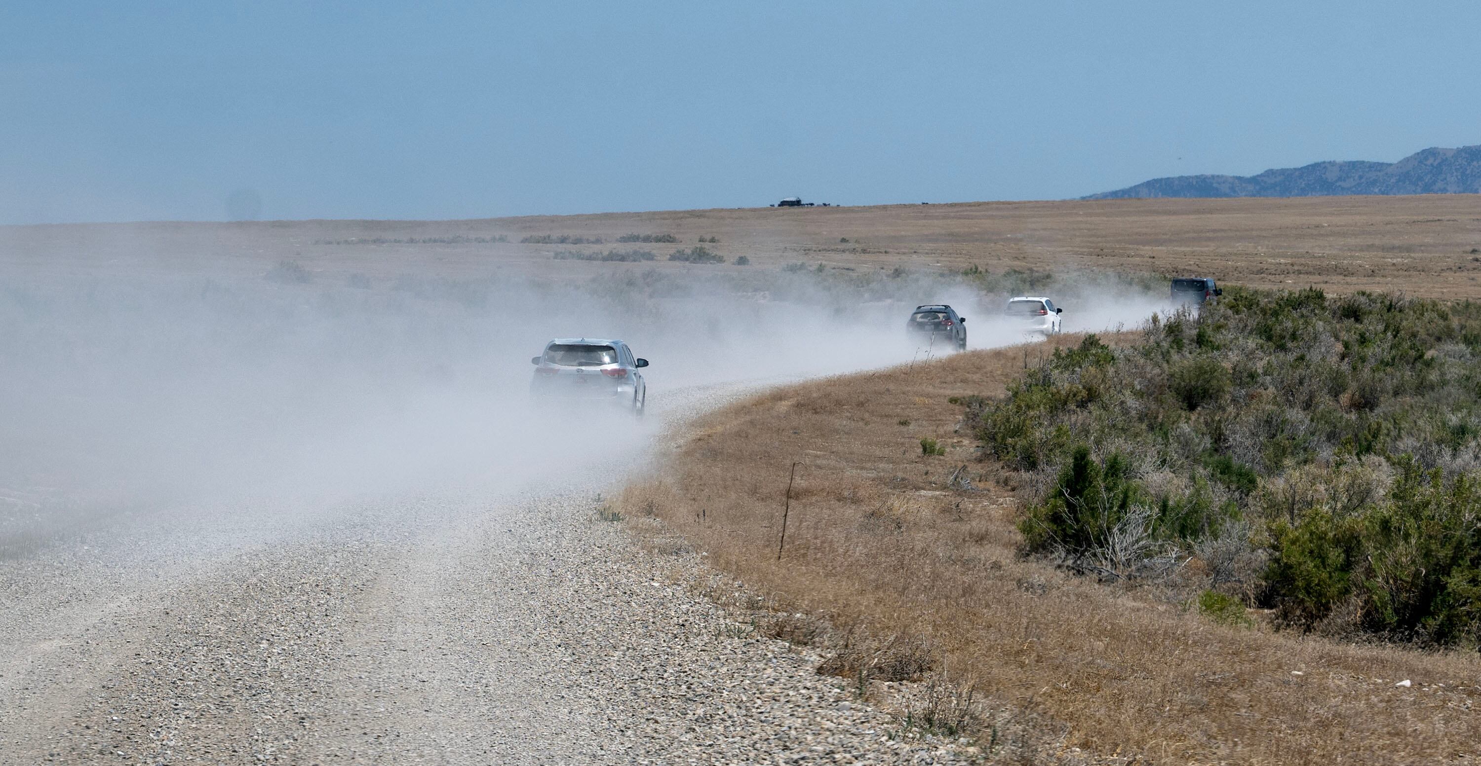 Several members of the media and other interested parties kick up dust as they take a tour of the Hansel Valley and surrounding areas near the proposed data center in Box Elder County on July 13. The project is facing mounting public scrutiny over its unprecedented scale, fast-tracked approval process and unknown impacts.