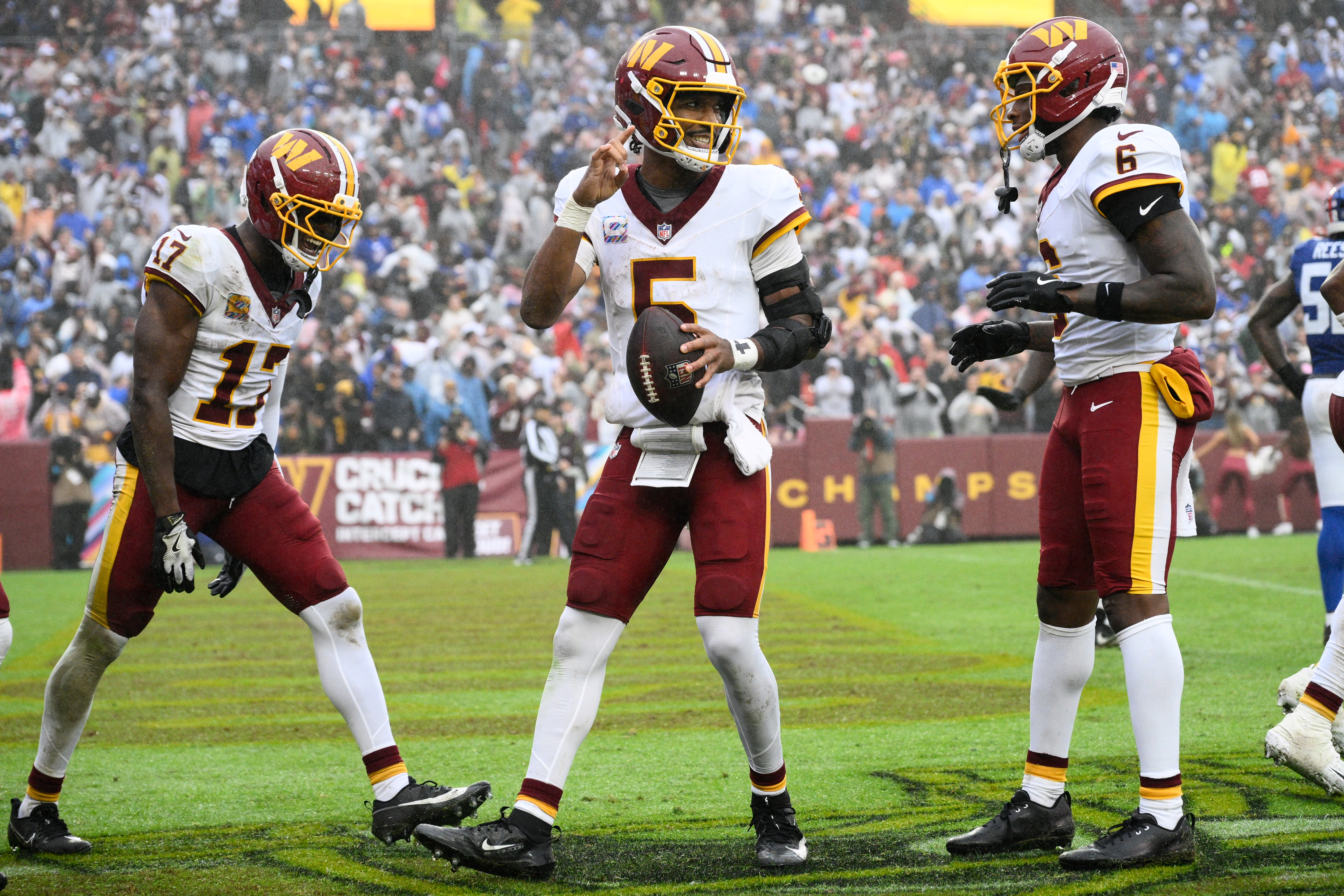 Washington Commanders quarterback Jayden Daniels (5) celebrates with teammates Terry McLaurin (17) and Dyami Brown (6) after scoring a touchdown during the second half of an NFL football game against the New York Giants in Landover, Md., Sunday, Oct. 11, 2026. 