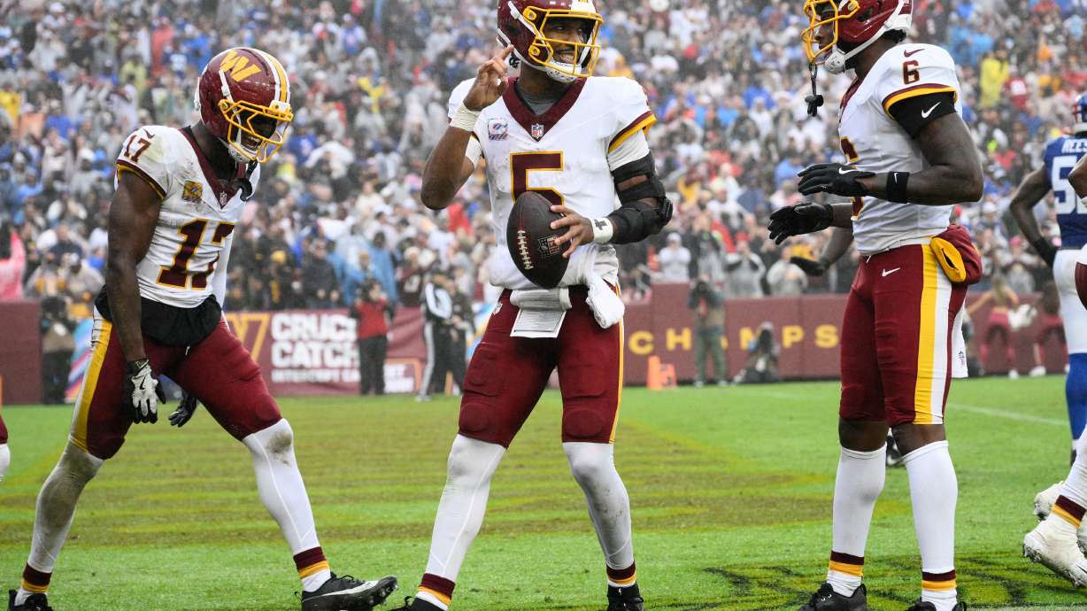 Washington Commanders quarterback Jayden Daniels (5) celebrates with teammates Terry McLaurin (17) and Dyami Brown (6) after scoring a touchdown during the second half of an NFL football game against the New York Giants in Landover, Md., Sunday, Oct. 11, 2026.