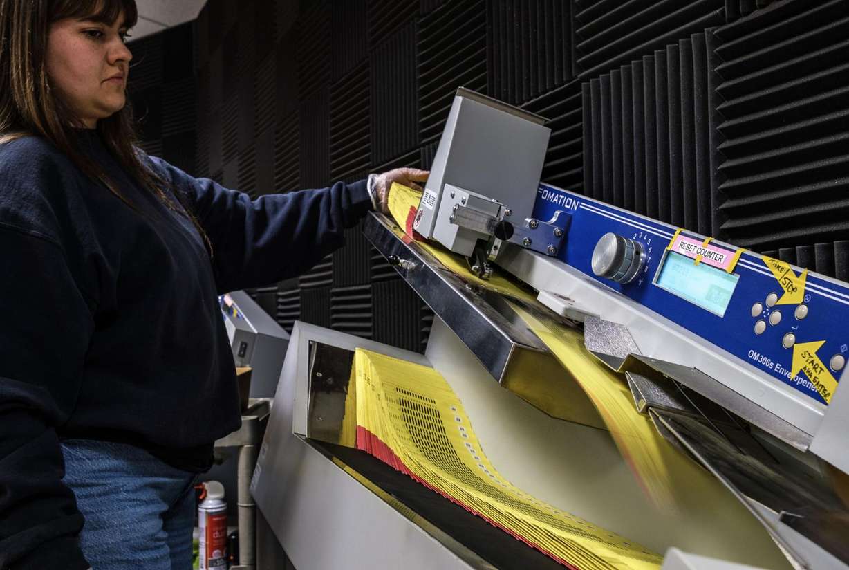 Janalyn Christensen feeds paper ballots through an “envelopener” machine at the Salt Lake County Government Center on June 23.