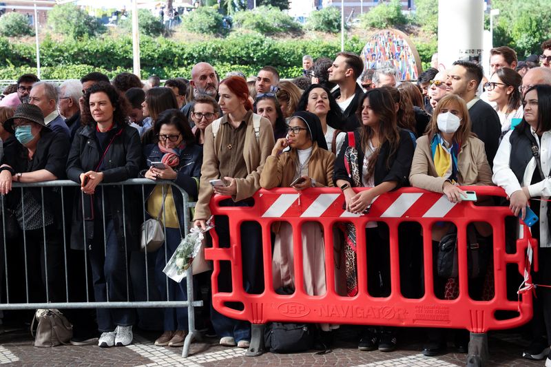 People wait for the Pope Leo's arrival at Gemelli Hospital, where he was to be hospitalized to undergo surgery to remove a small growth on his lung, in Rome, Italy, Tuesday. The Vatican said his surgery went well and as planned.