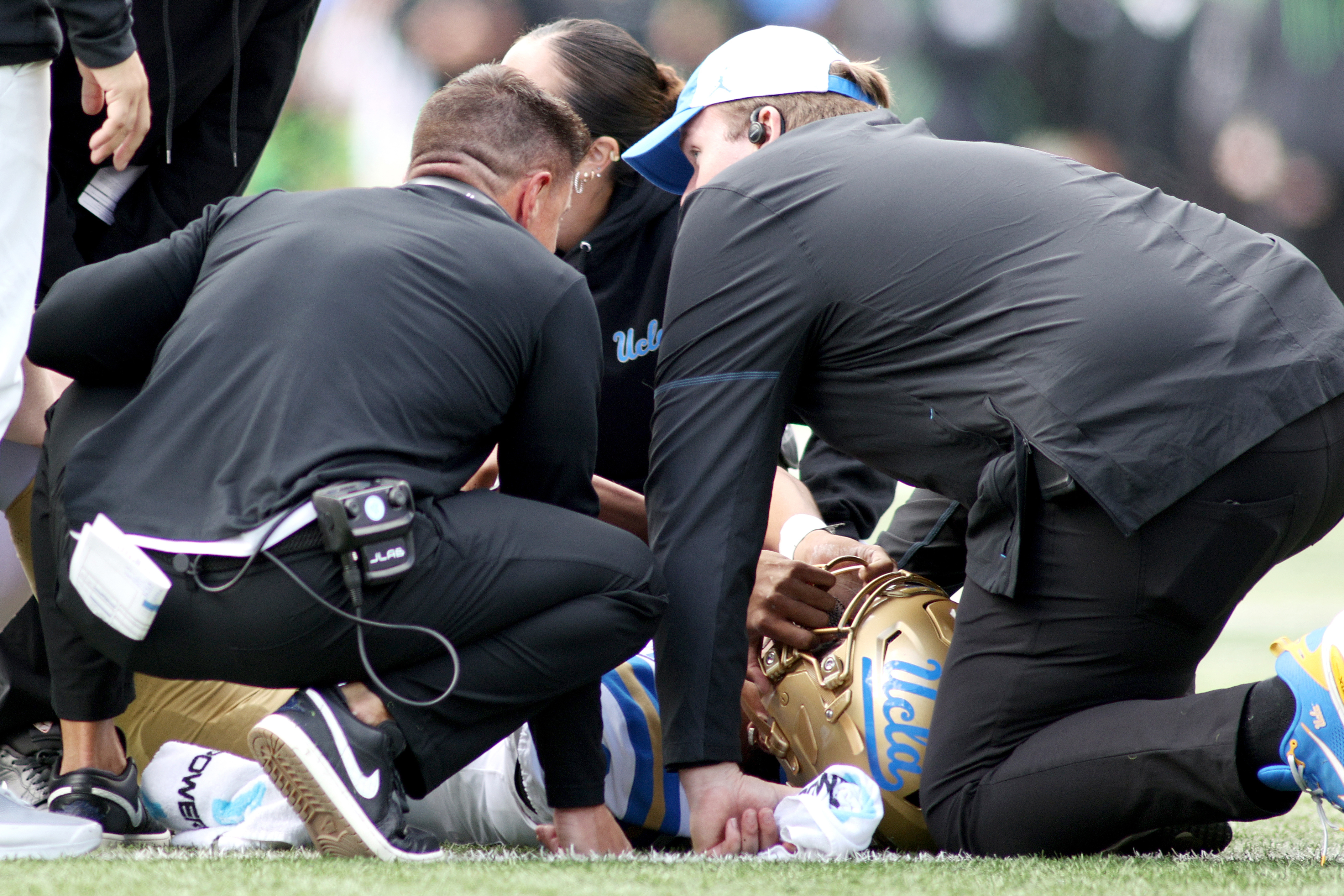 UCLA quarterback Nico Iamaleava (9) is examined by head coach Bob Chesney, left, and medical staff during the first half of an NCAA college football game against Oregon, Saturday, Oct. 10, 2026, in Eugene, Ore. 