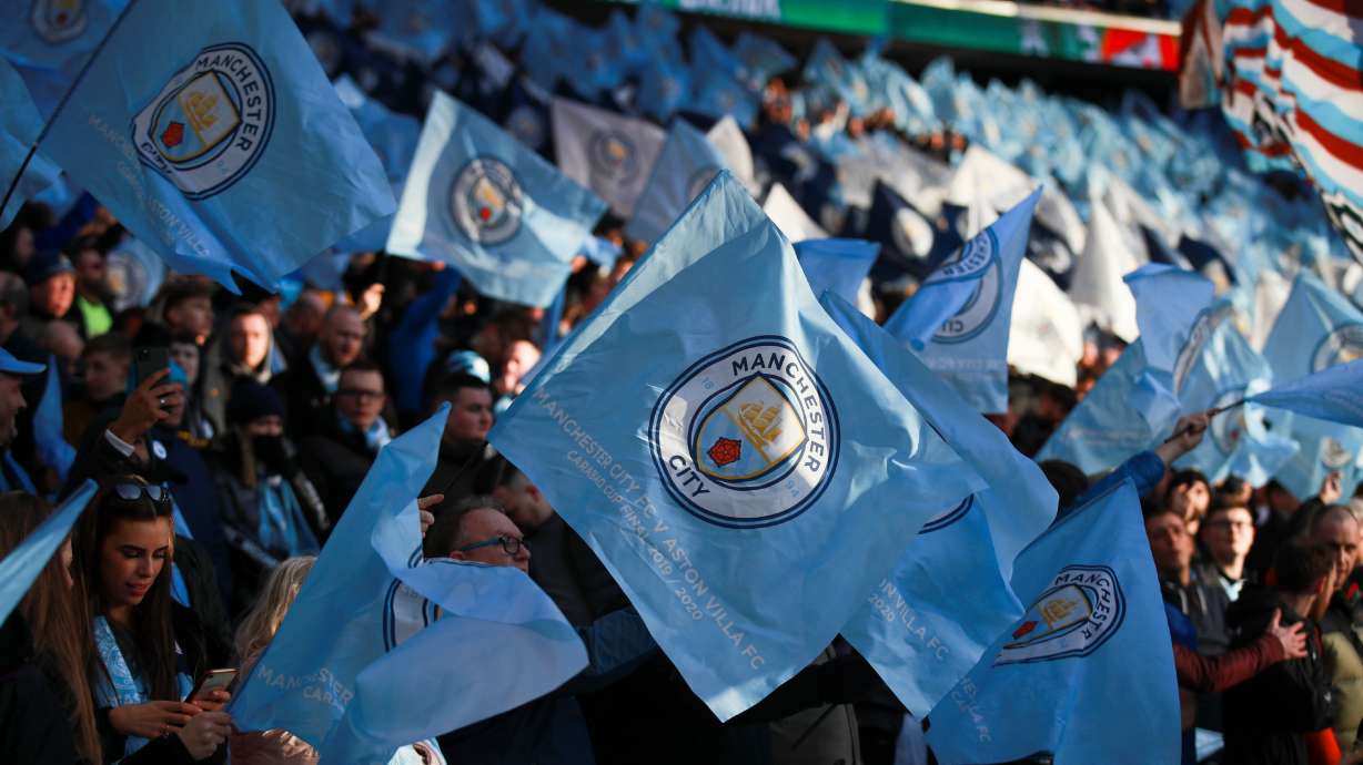 FILE - Manchester City fans wave the team's flag prior to the League Cup soccer match final between Aston Villa and Manchester City, at Wembley stadium, in London, England, Sunday, March 1, 2020.