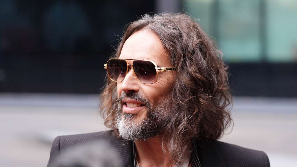 Russell Brand speaks to the media as he arrives at Southwark Crown Court in London, Wednesday. A prosecutor called Brand a "ruthless" sexual predator at the opening of his rape and sexual assault trial.
