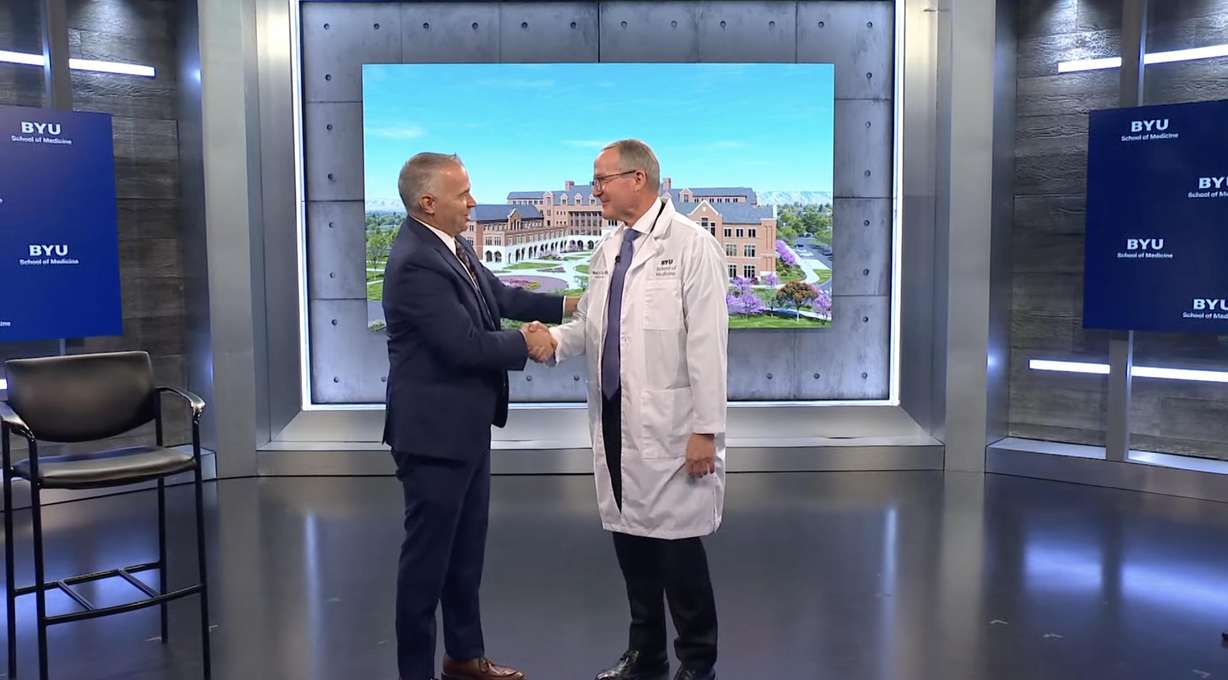 Brigham Young University President Shane Reese (left) shakes hands with Dr. Mark Ott, Dean of BYU's School of Medicine, after announcing the BYU's medical school received national accreditation.
