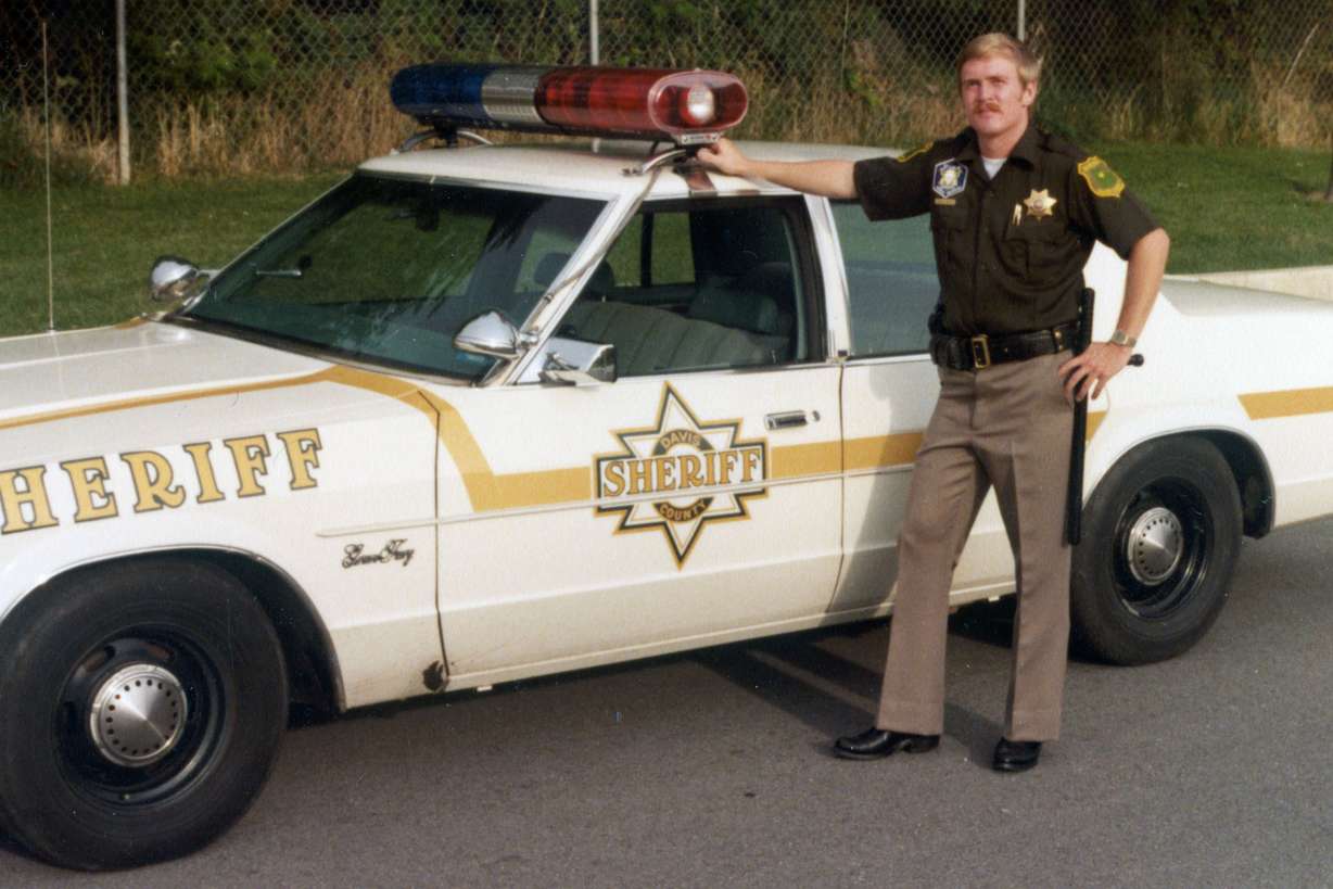 Brian Weese served as a deputy and paramedic for the Davis County Sheriff's Office during the 1980s. This image from Weese's scrapbook shows him standing alongside a sheriff's patrol car.