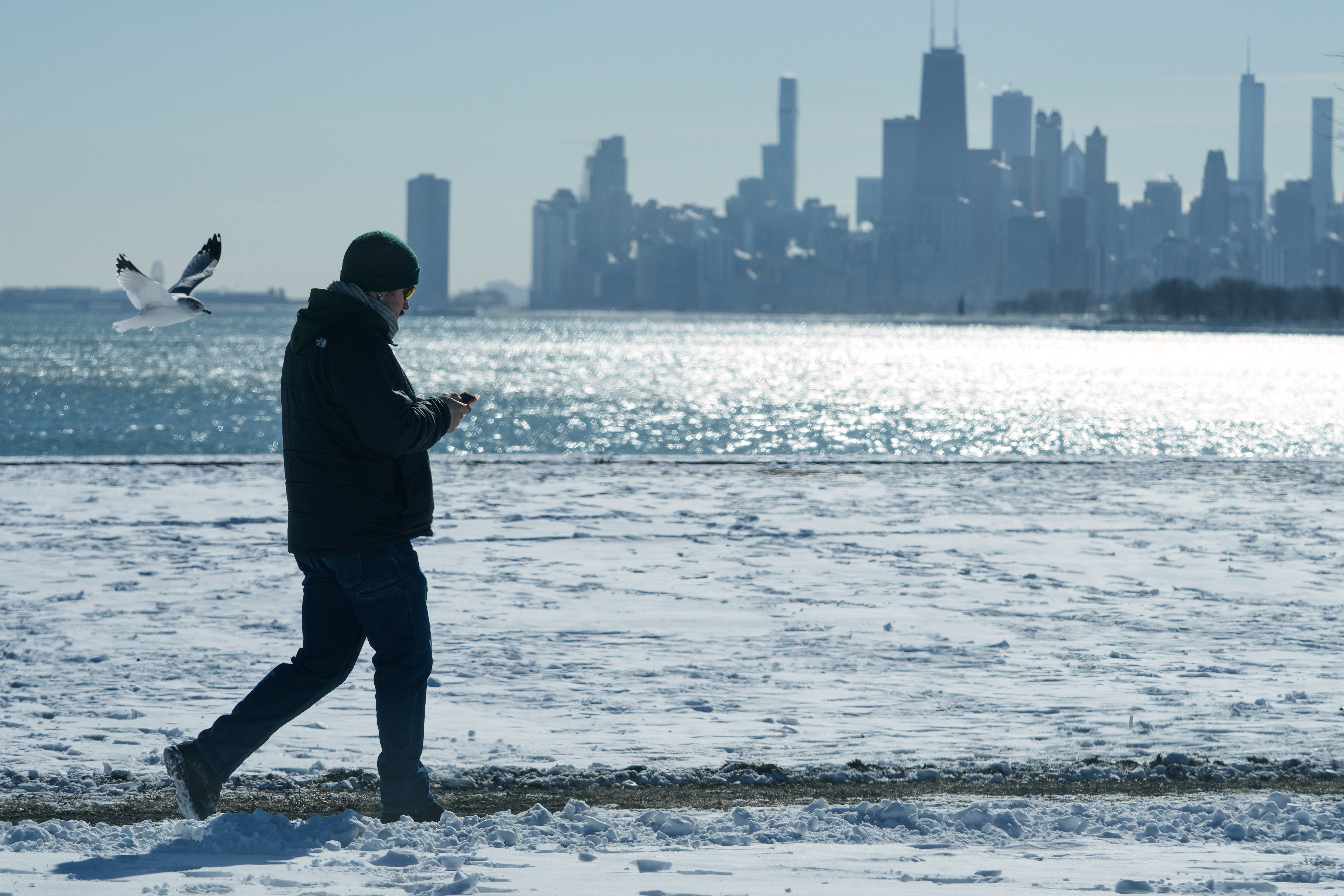 A person walks near the snow-covered sand at Lake Michigan in Chicago, Jan. 28. While El Nino is expected to be at its strongest this winter, it doesn't necessarily mean an increase of rain or snow at a certain location.