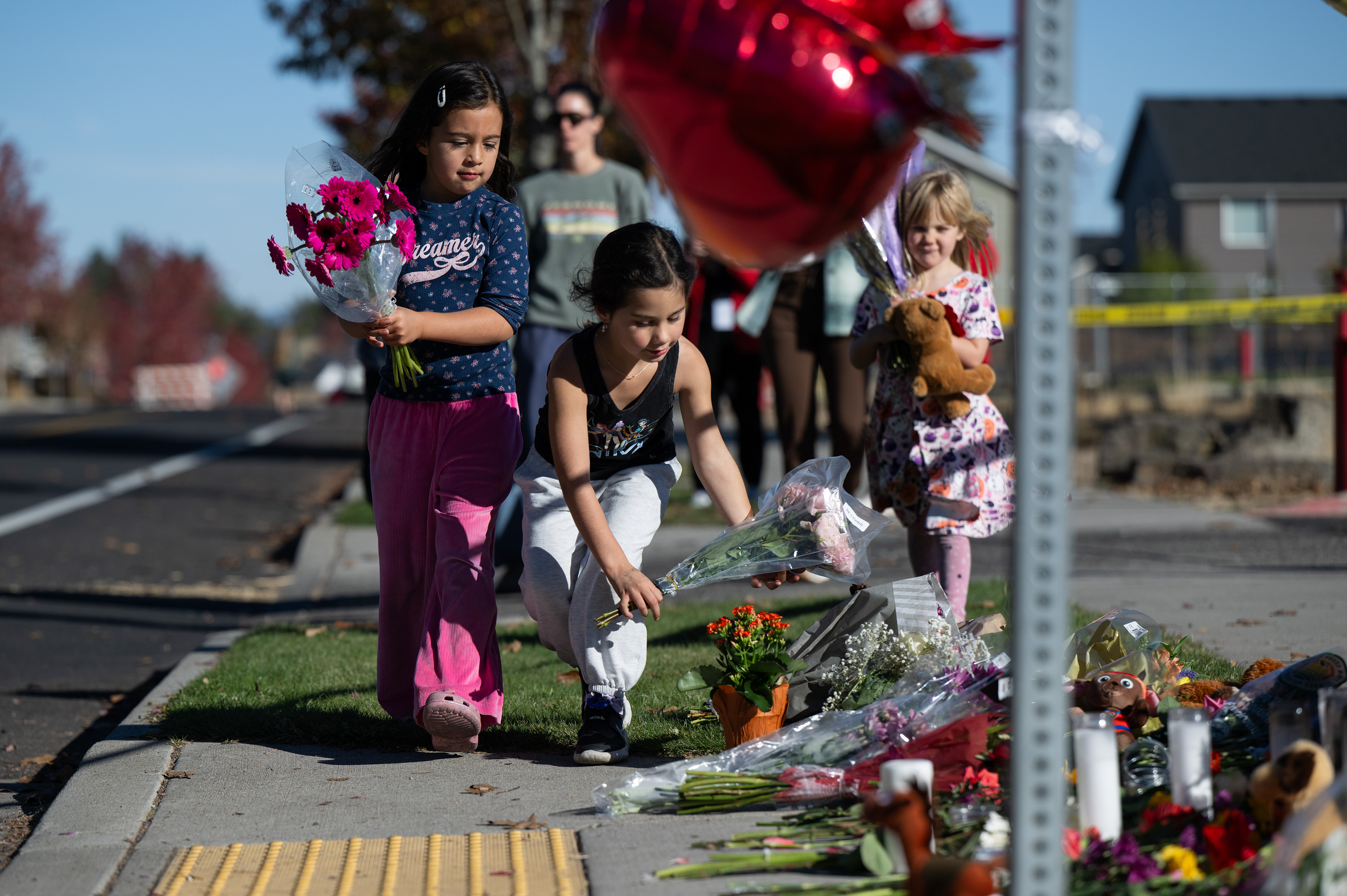Children place flowers at a makeshift memorial outside Silver Rail Elementary in Bend, Ore., Friday, a day after a deadly shooting. Four people were killed, including the shooter, in the attack.