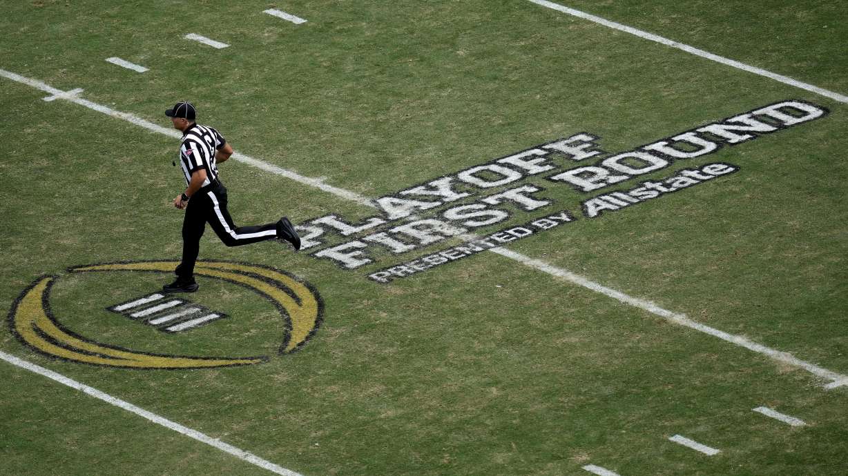 FILE - A game official runs across the College Football Playoff logo on Kyle Field during the third quarter in the first round of the College Football Playoff between Miami and Texas A&M, Dec. 20, 2025, in College Station, Texas.