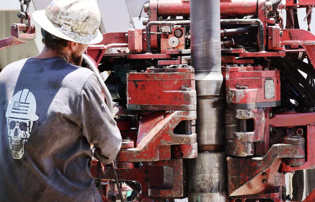 A crew member threads two lengths of pipe as they work on a drilling rig at the FORGE geothermal demonstration site near Milford on July 6, 2023. Media were given a tour of the facility.