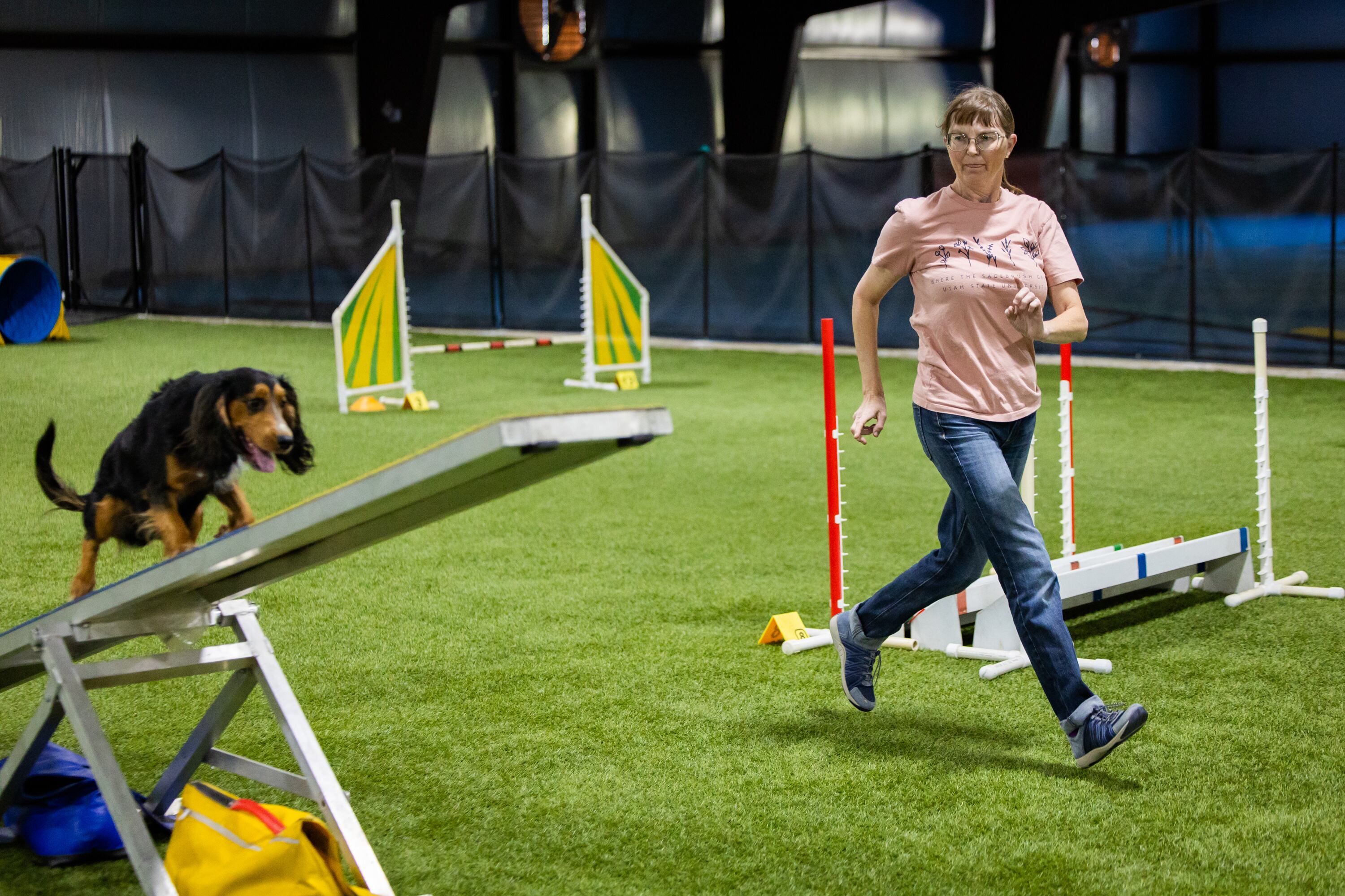 Tracy Mazur, a dog trainer and dog show judge who has been selected to be a judge at the Westminster Dog Show in New York in January 2027, right, demonstrates agility training with her dog Quill for the Deseret News at Versa Dog Training, where she trains her dogs, in Layton on Sept. 30.