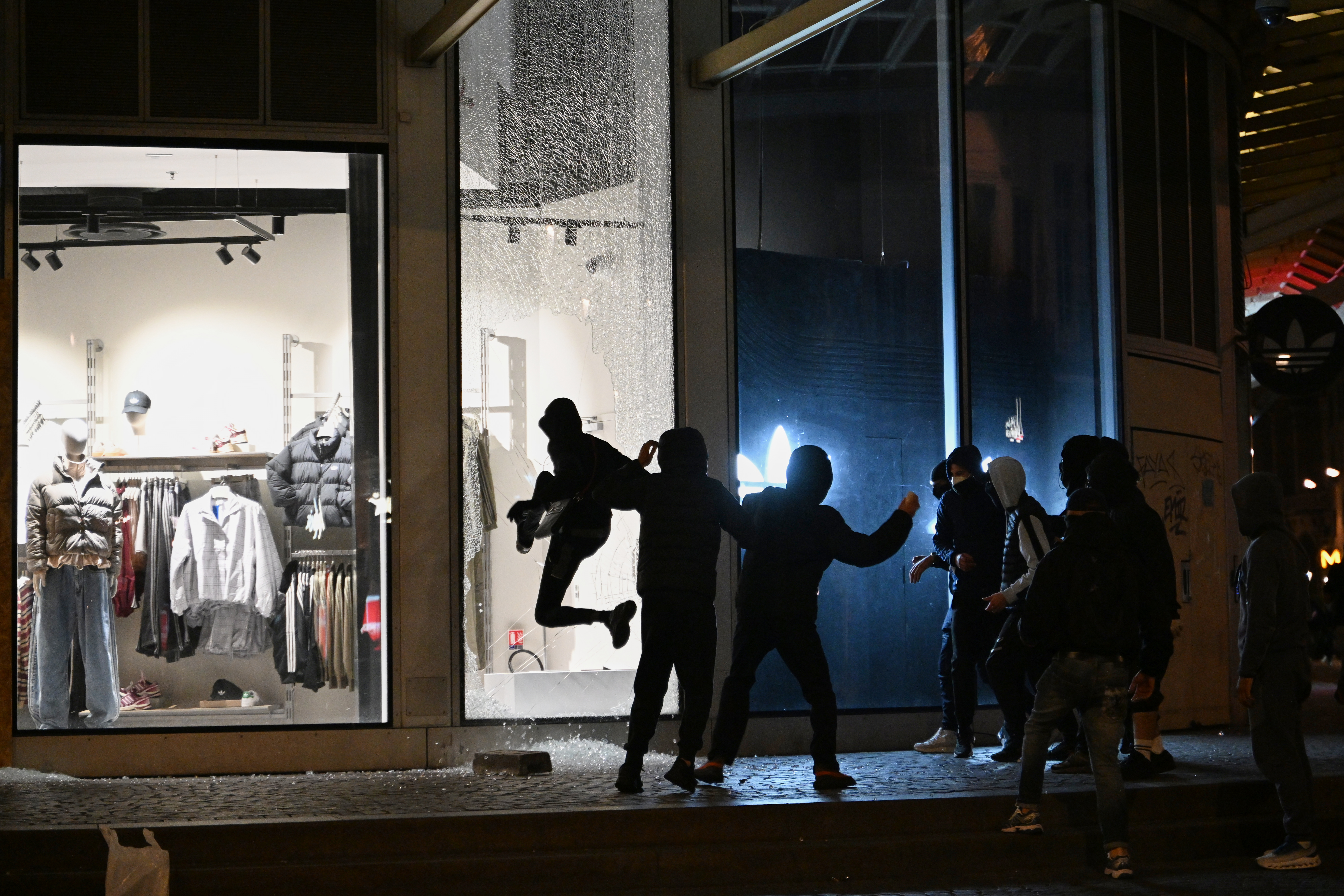 Youths break a store window during clashes between protestors and police in Paris, Sunday, Oct. 18, 2026. 