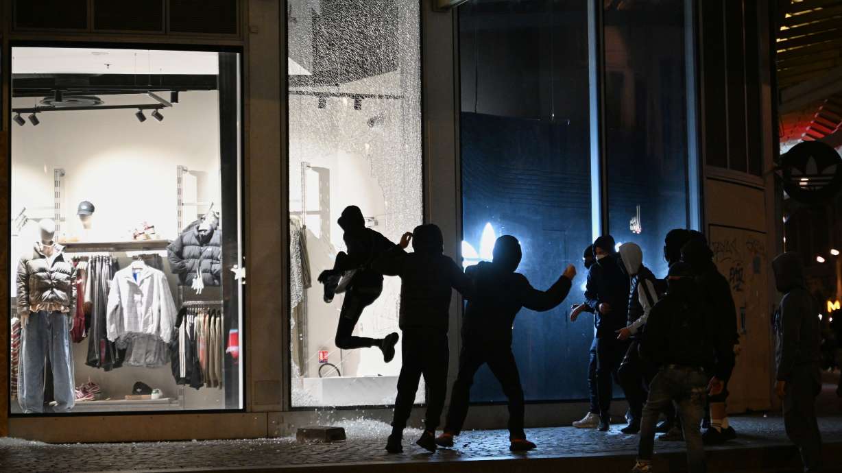 Youths break a store window during clashes between protestors and police in Paris, Sunday, Oct. 18, 2026.