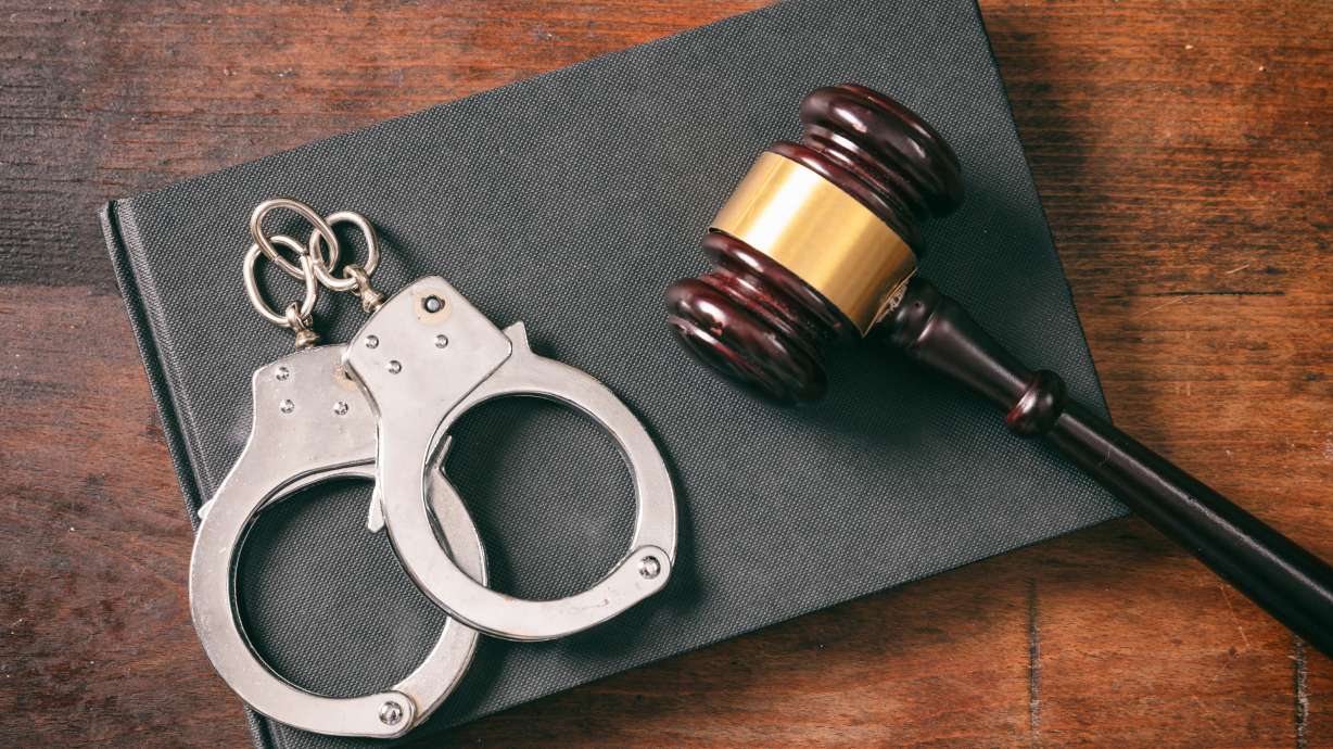 Handcuffs, gavel on book on a wooden background, top view