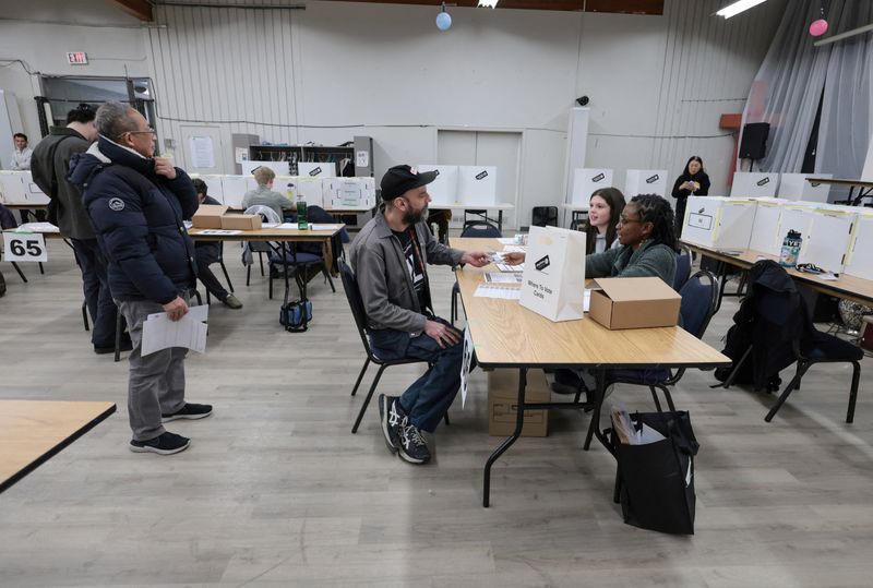 People line up as they register to vote in a voting station during the Alberta Referendum as Albertans head to the polls in Calgary, Alberta, Canada, Monday.