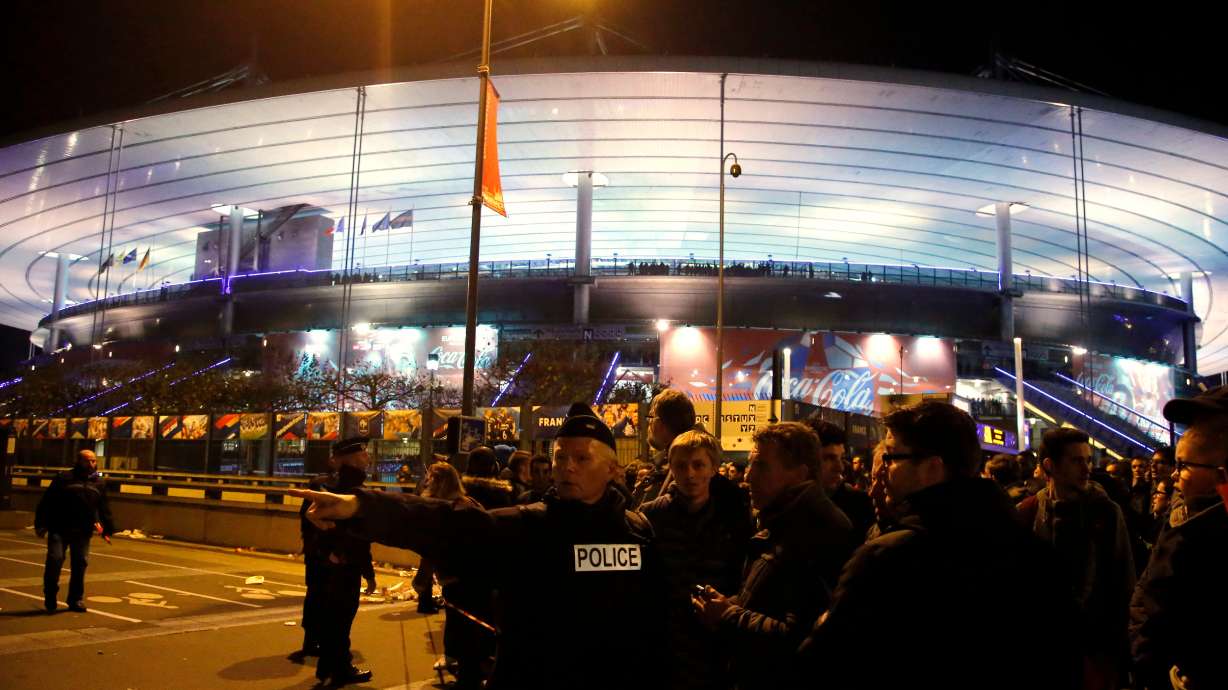 FILE - A police officer directs people outside the Stade de France stadium during the international friendly soccer France against Germany, in Saint Denis, outside of Paris, France, Nov. 13, 2015.