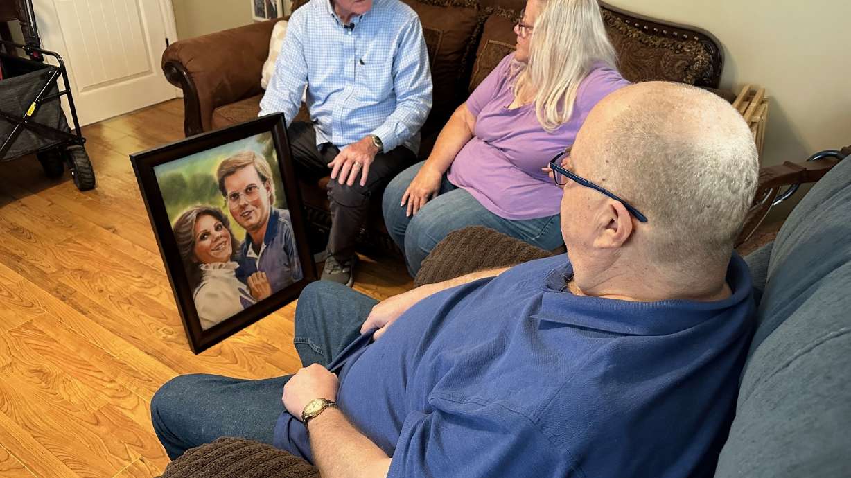 Artist JR Johansen presents a portrait to Cindy and Greg Thredgold. Johansen has painted 183 portraits of fallen missionaries.
