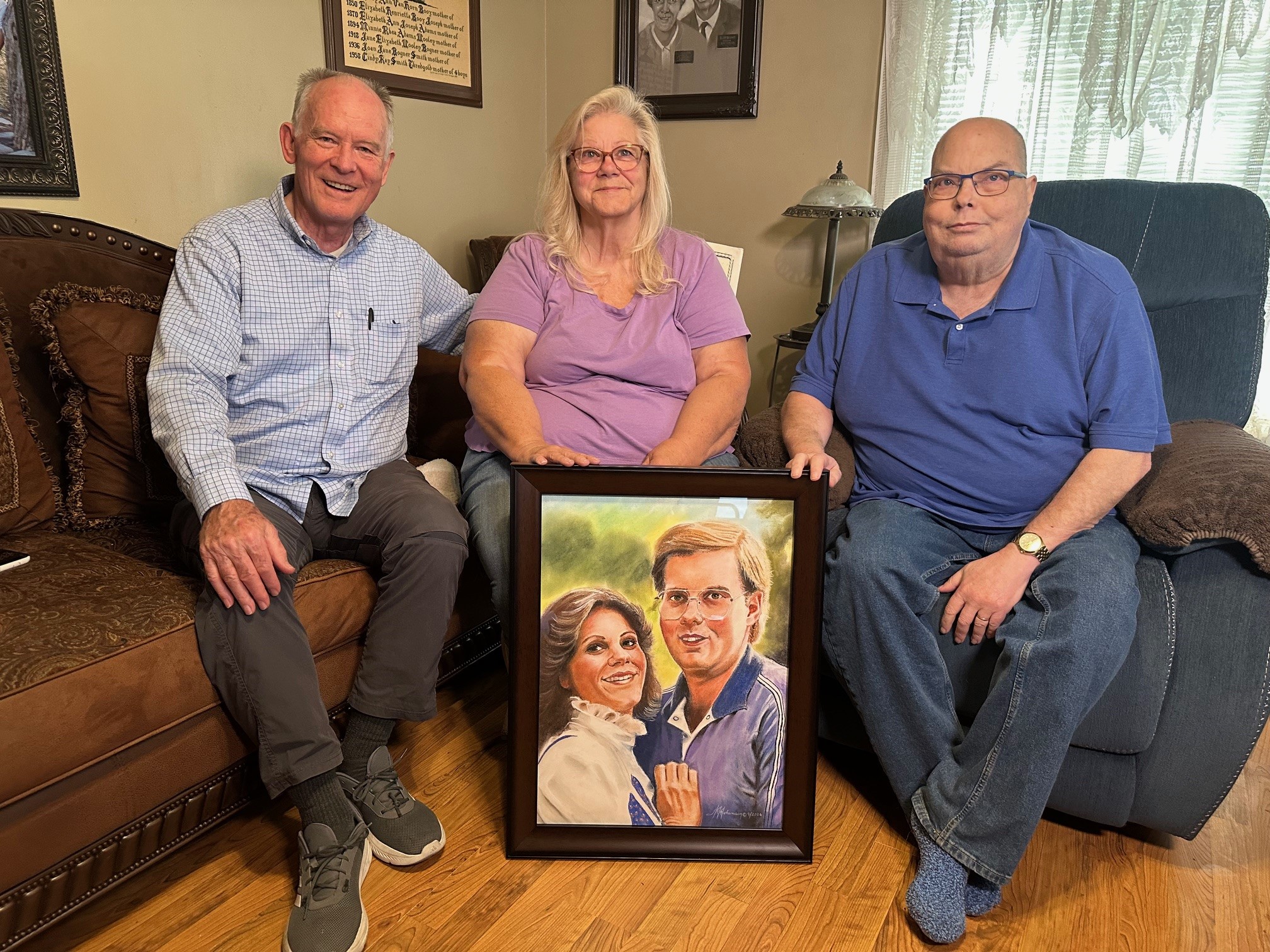 Artist JR Johansen presents a portrait to Cindy and Greg Thredgold. Johansen has painted 183 portraits of fallen missionaries.