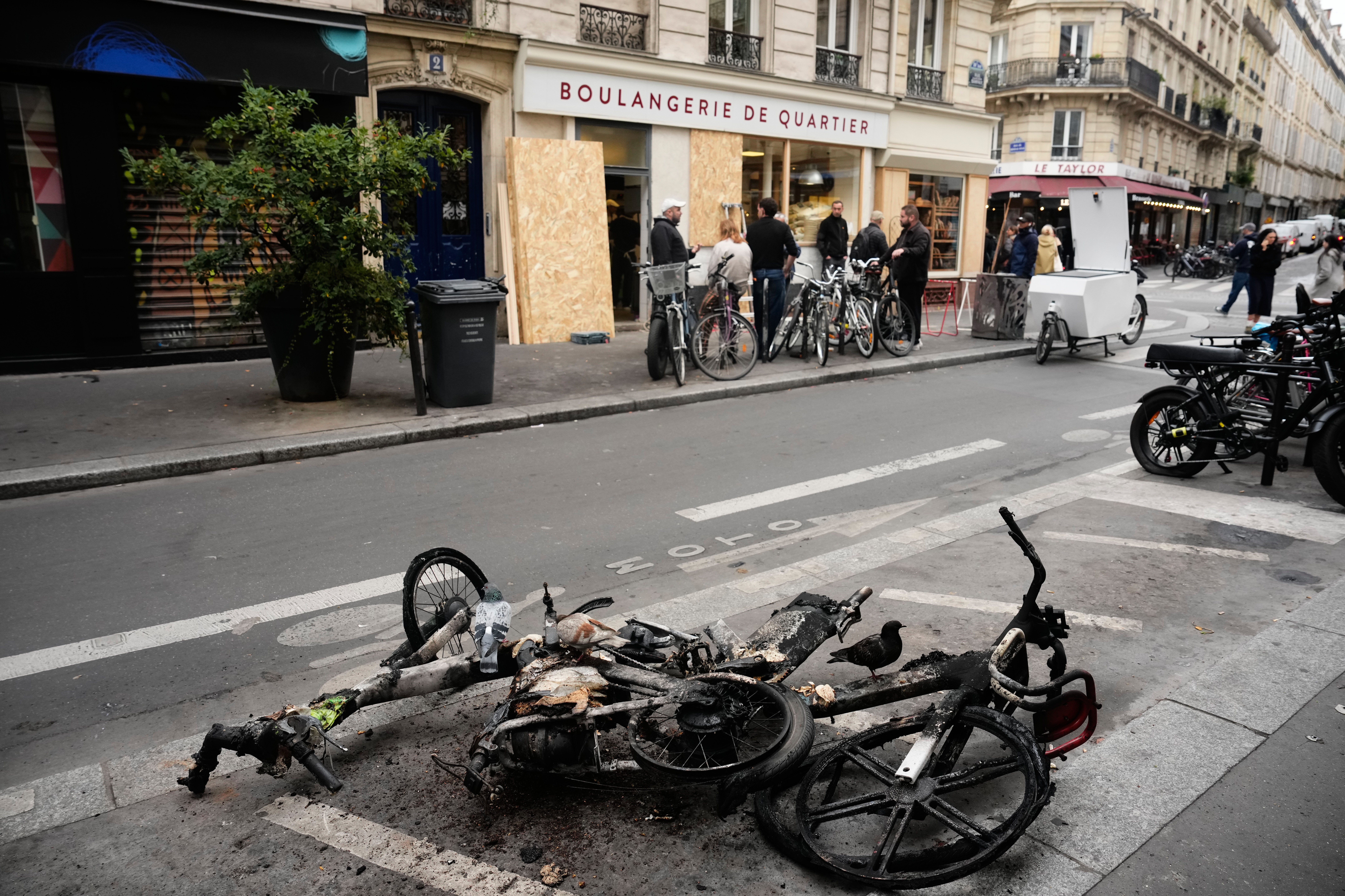 Burned electric bicycles lie on the road near a bakery after weekend protests over the cost of living turned into rioting and looting across France, in Paris, Wednesday, Oct. 21, 2026. 