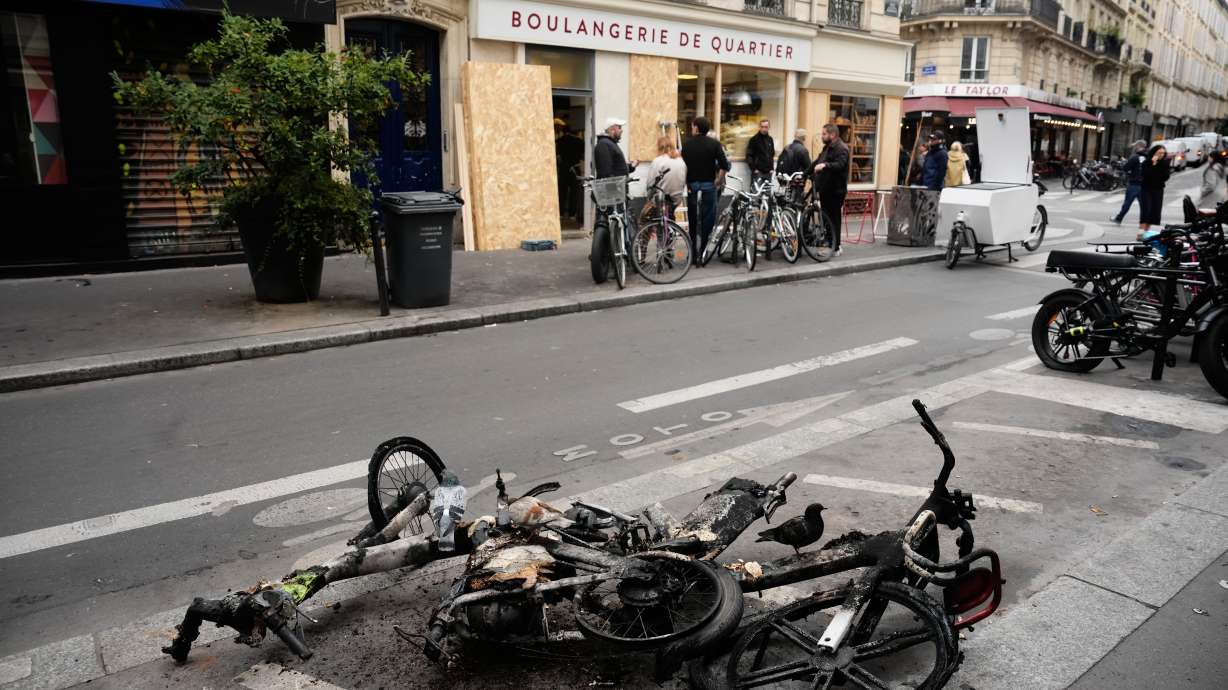 Burned electric bicycles lie on the road near a bakery after weekend protests over the cost of living turned into rioting and looting across France, in Paris, Wednesday, Oct. 21, 2026.