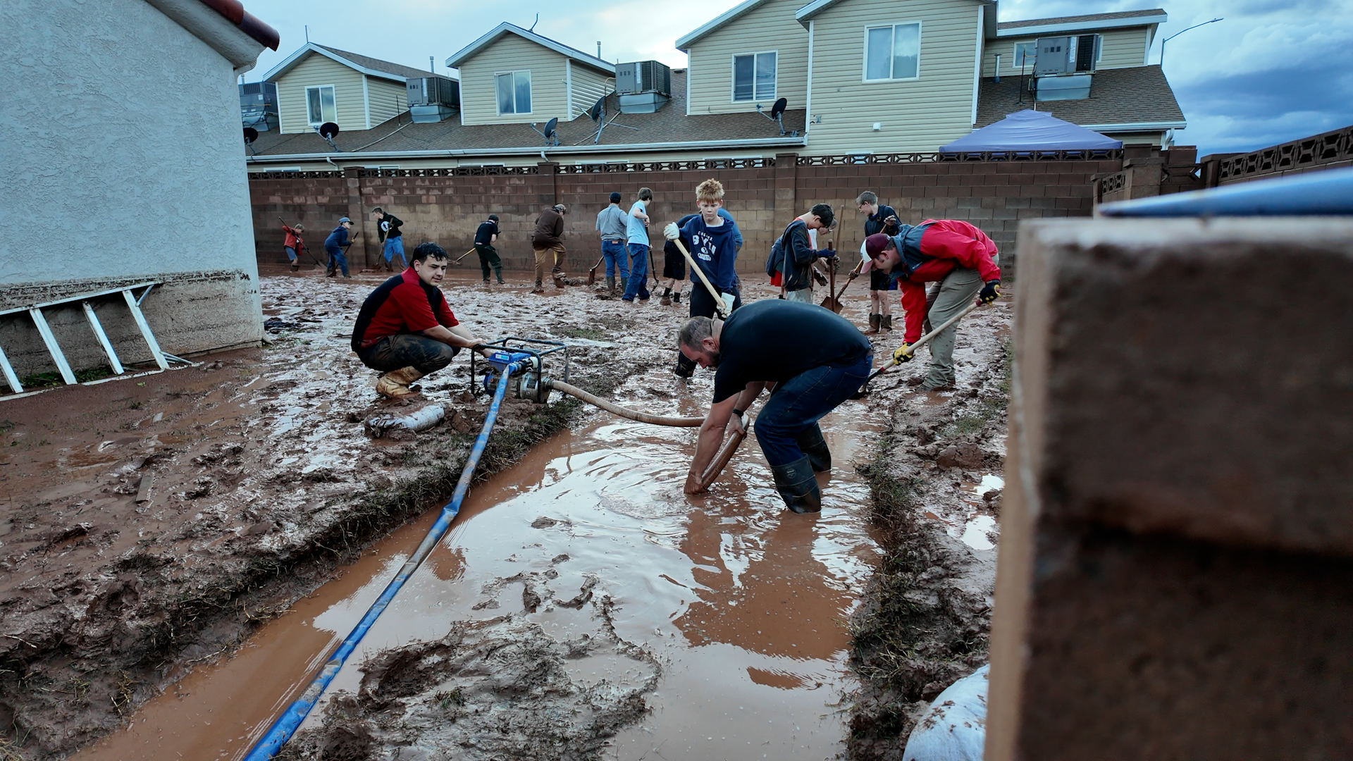 Volunteers help a homeowner clear mud from around her home.