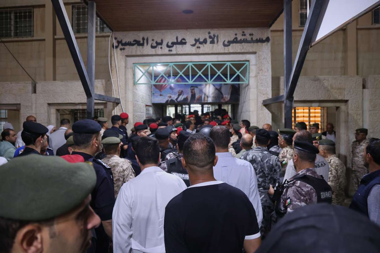 Residents gather as soldiers and security officers block the entrance to Prince Ali Military Hospital during King Abdullah II's visit to people wounded in a shooting at a Greek Orthodox church during a funeral hours earlier, in Karak, Jordan, Friday.