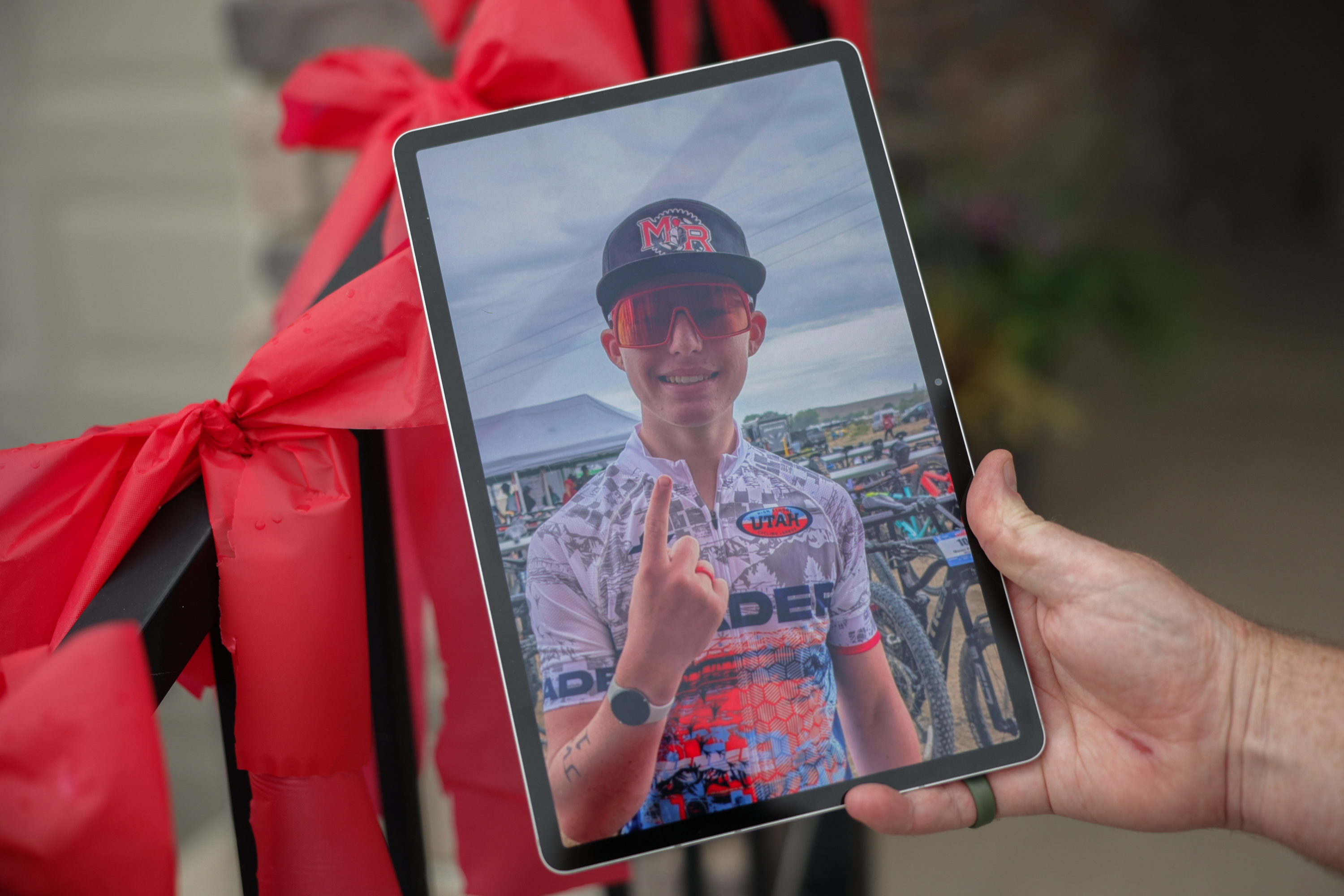 Nick Dutson holds a photo of his son, Landon Dutson. The family returned home to the streets of their community lined with red ribbons in his honor.