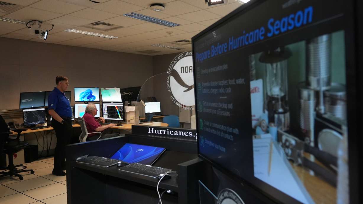 Senior hurricane specialists Eric Blake, left, and Richard Pasch, right, work at the National Hurricane Center on the first day of hurricane season, June 1, in Miami.