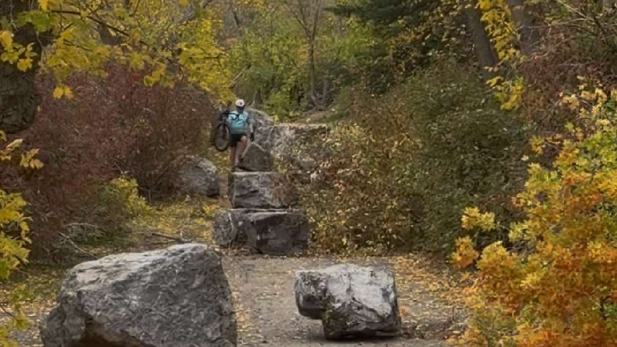 A bicyclist walks past debris from a rockslide in Provo Canyon Friday afternoon. Utah County officials said the trail is closed near the popular waterfall after the rockslide.