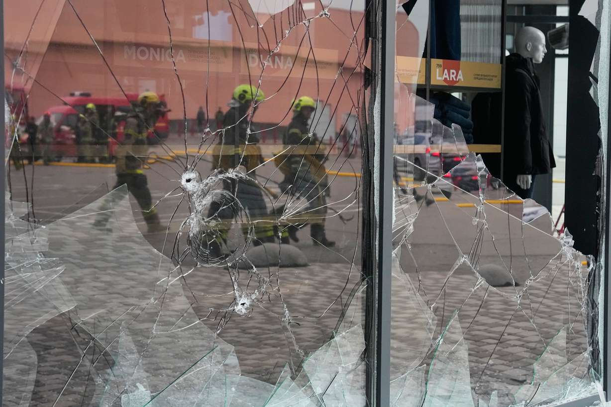 Firefighters are reflected in the broken glass after a Russian missile attack in central Kyiv, Ukraine, Thursday.