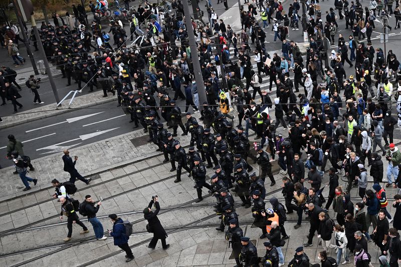 French CRS riot police monitor in front of the march as protesters arrive at the Porte de Vincennes during an authorised demonstration organised by labour unions in Paris as part of nationwide protests called by the "Yellow Vests" movement joined by French high school and university students against the cost of living and rising fuel prices, in France, Saturday.