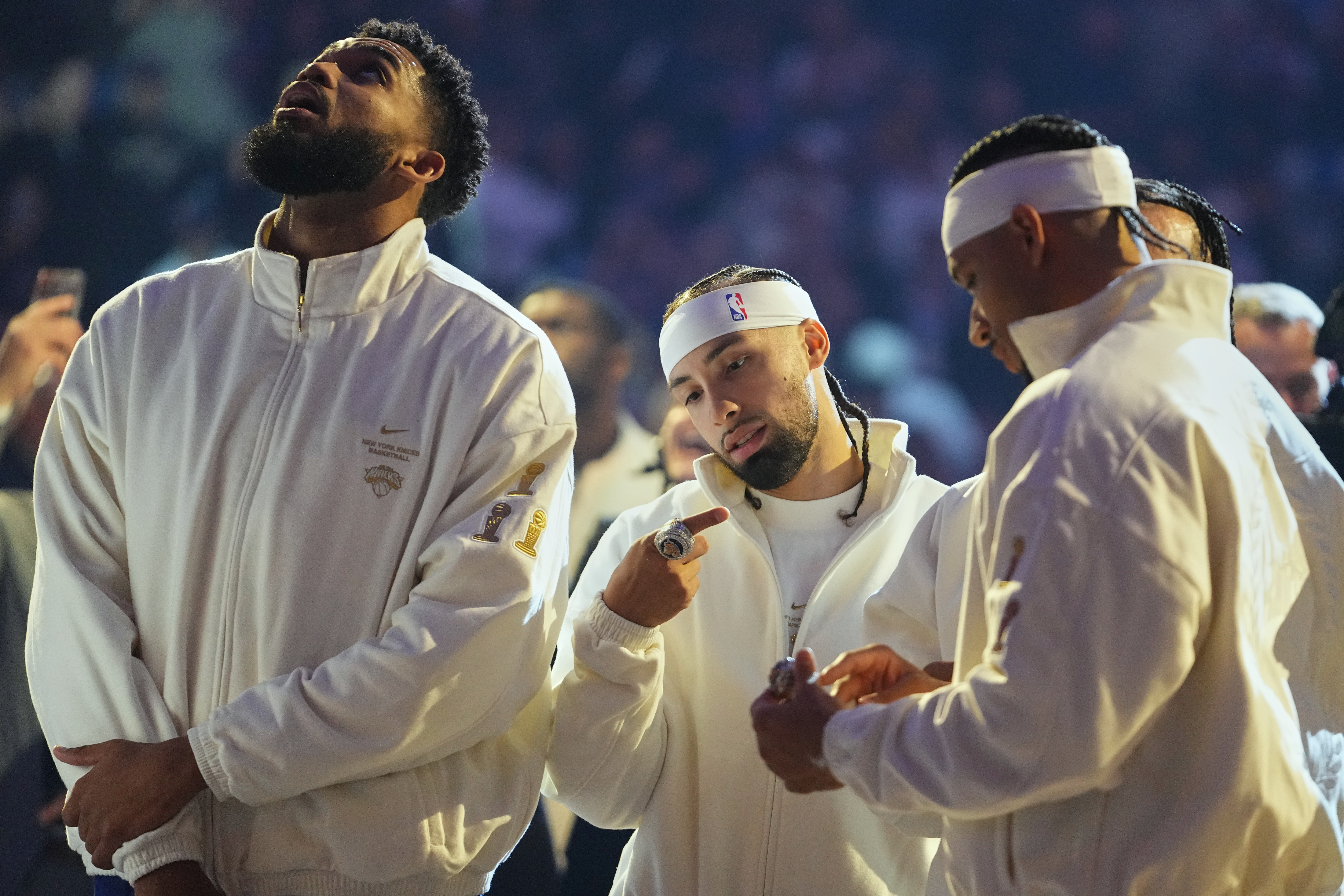 New York Knicks guard Jose Alvarado, center, looks at his 2025-26 World Champions ring alongside teammates center Karl-Anthony Towns, left, and guard Josh Hart before an NBA basketball game against the Philadelphia 76ers Tuesday, Oct. 20, 2026, in New York.