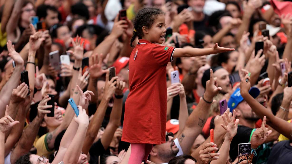A girl standing on a man's shoulders reaches out amid a crowd of supporters of Brazilian President Luiz Inacio Lula da Silva, who is running for reelection, during his final campaign rally, a day ahead of the presidential runoff election in Sao Paulo, Brazil, Saturday.