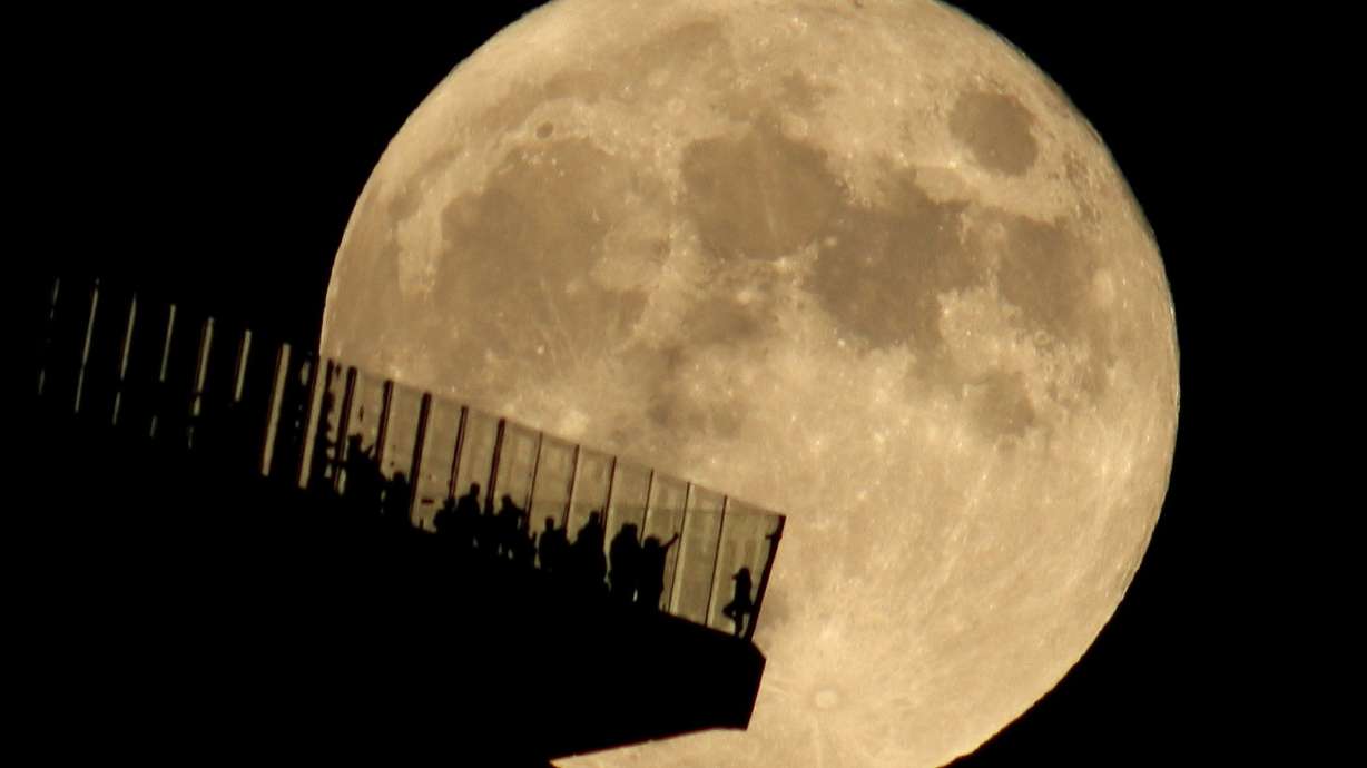 People standing on the Edge NYC watch a full hunter's moon rising in New York in October 2021.