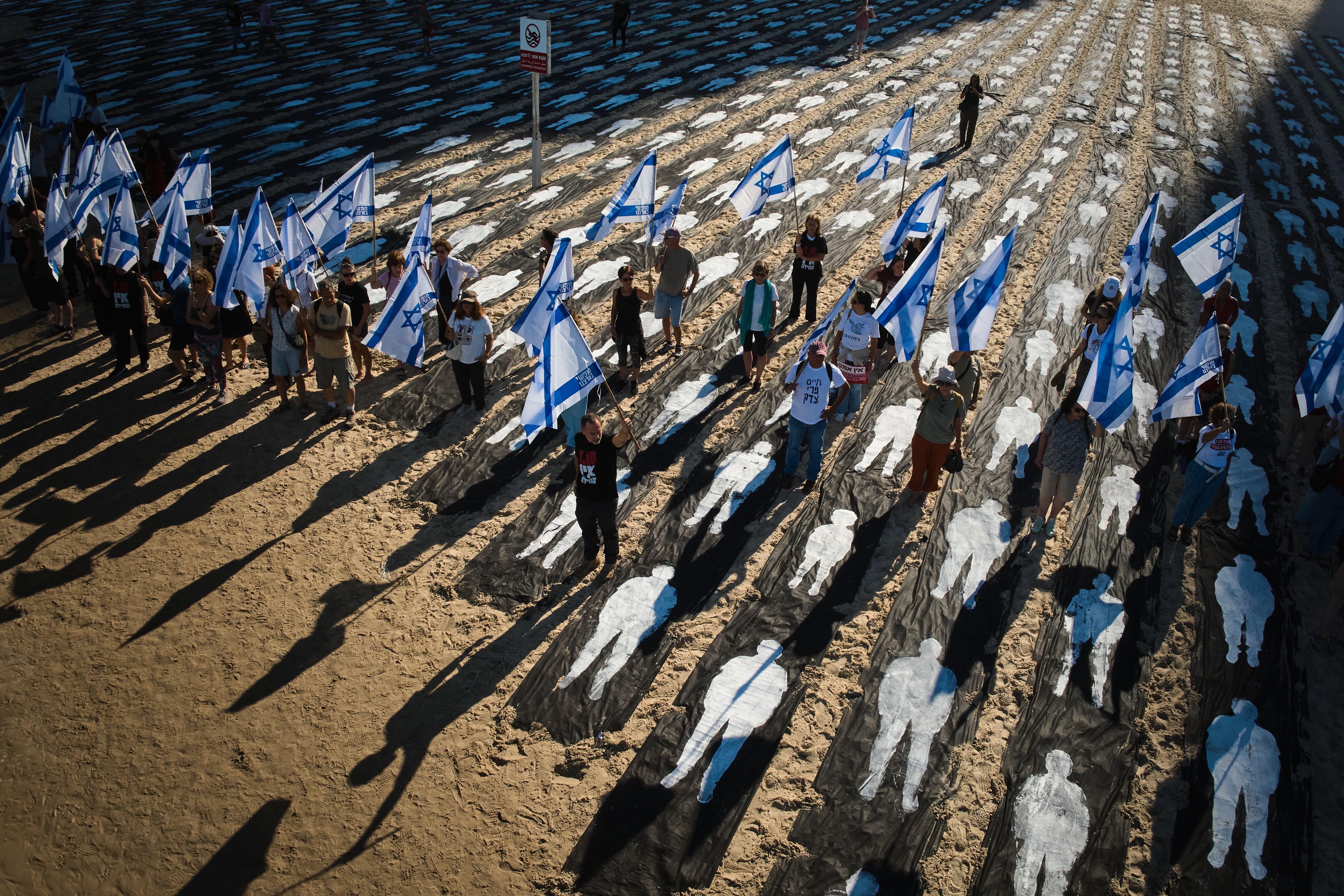 People carrying Israeli flags walk through an installation marking the third anniversary of the Oct. 7, 2023, Hamas attack on Israel, on the beachfront in Tel Aviv, Israel, Oct. 7, 2026.