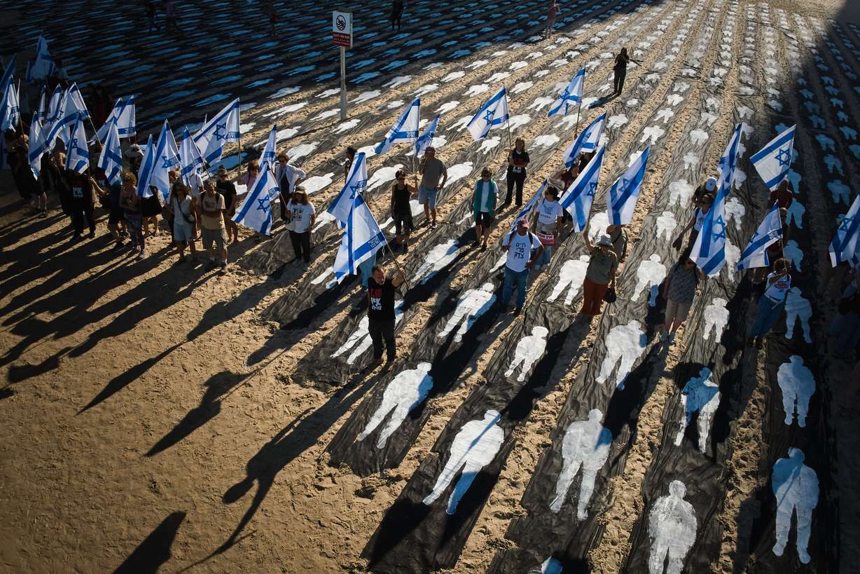 People carrying Israeli flags walk through an installation marking the third anniversary of the Oct. 7, 2023, Hamas attack on Israel, on the beachfront in Tel Aviv, Israel, Oct. 7, 2026.