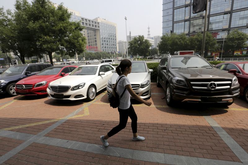 A woman walks past Mercedes Benz cars displayed for sale outside a store in Beijing, China August 11, 2015.