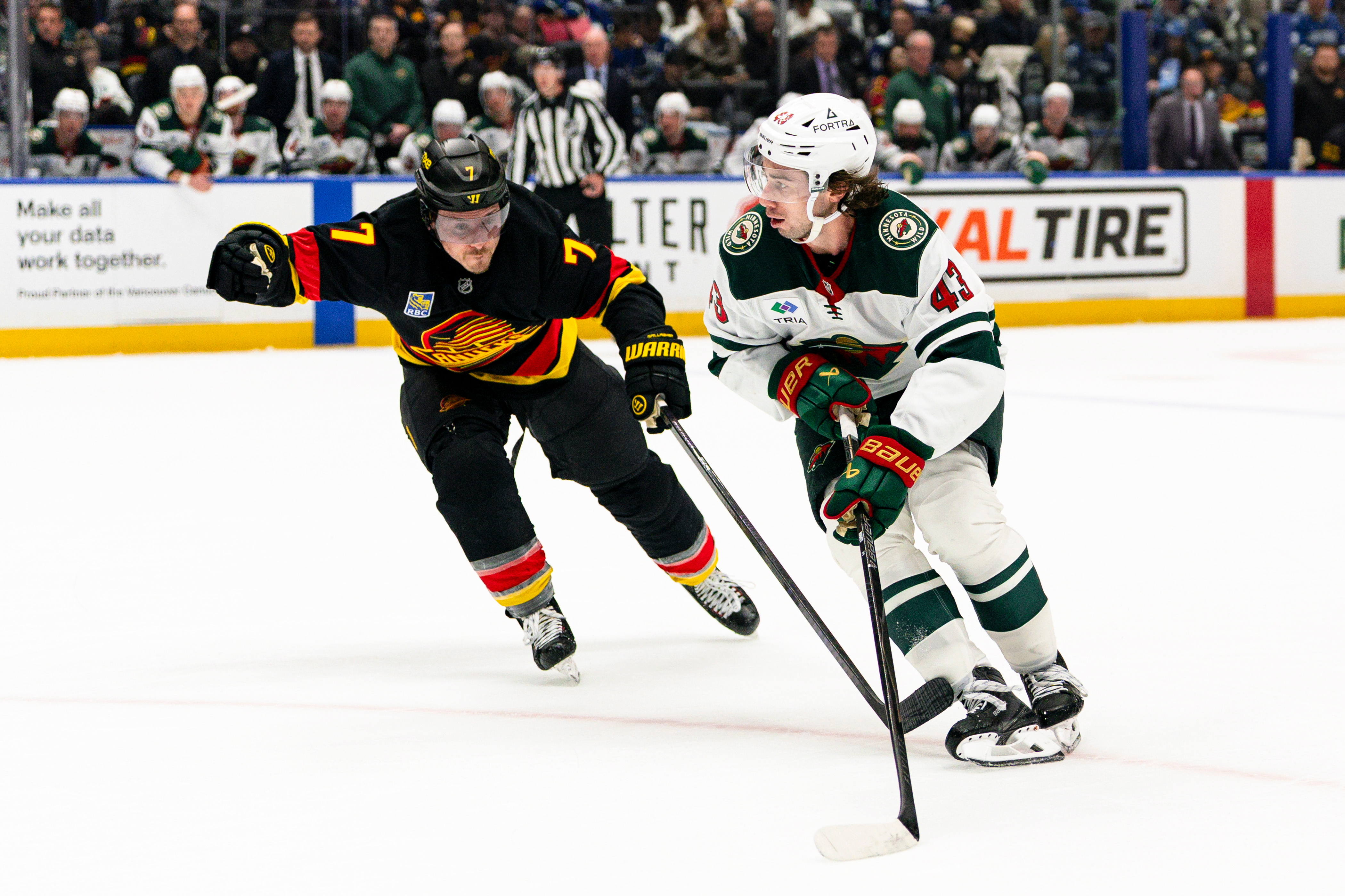 Minnesota Wild's Quinn Hughes (43) skates past Vancouver Canucks' Brendan Gallagher (7) during the second period of an NHL hockey game, in Vancouver, British Columbia, Sunday, Oct. 25, 2026. 