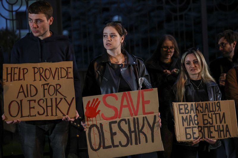 People hold posters as they participate in a rally demanding the establishment of a humanitarian corridor to evacuate Ukrainian civilians from the town of Oleshky in Kherson region, amid Russia's attack on Ukraine, in Kyiv, Oct. 6. A local ceasefire went into effect in Oleshky on Tuesday.